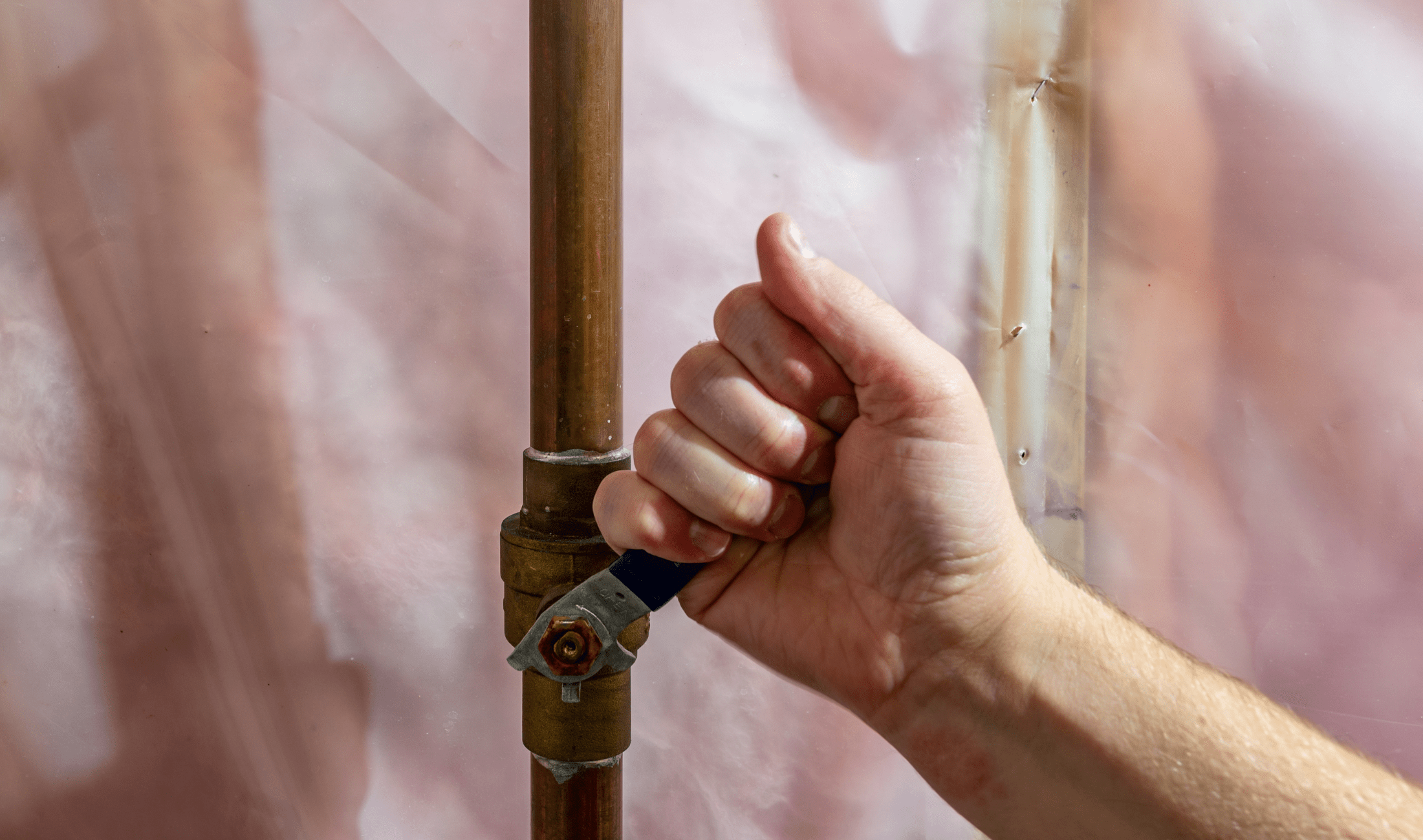 A hand turning a water valve in a home.