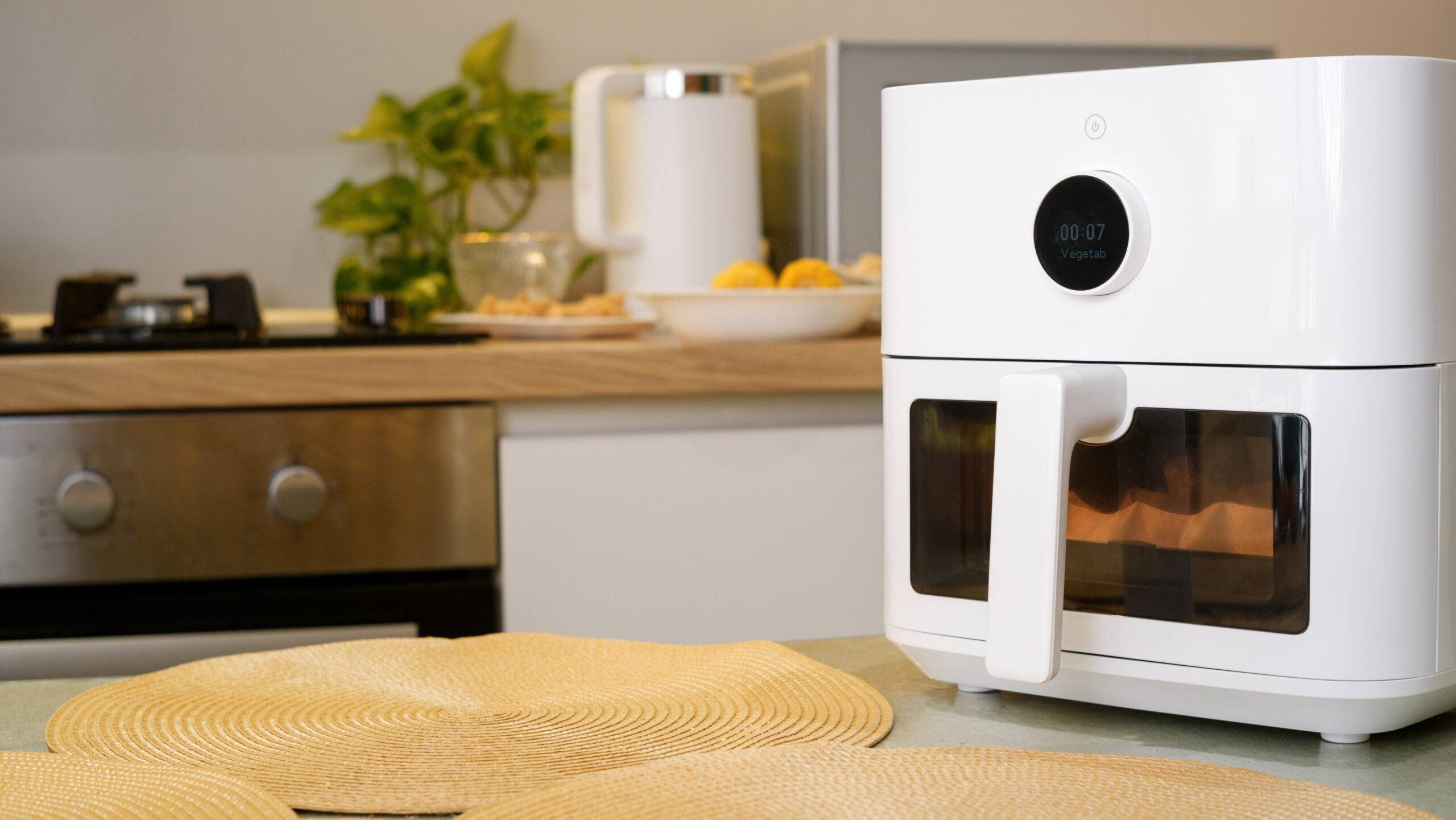 Modern white air fryer cooking some food, placed on kitchen counter
