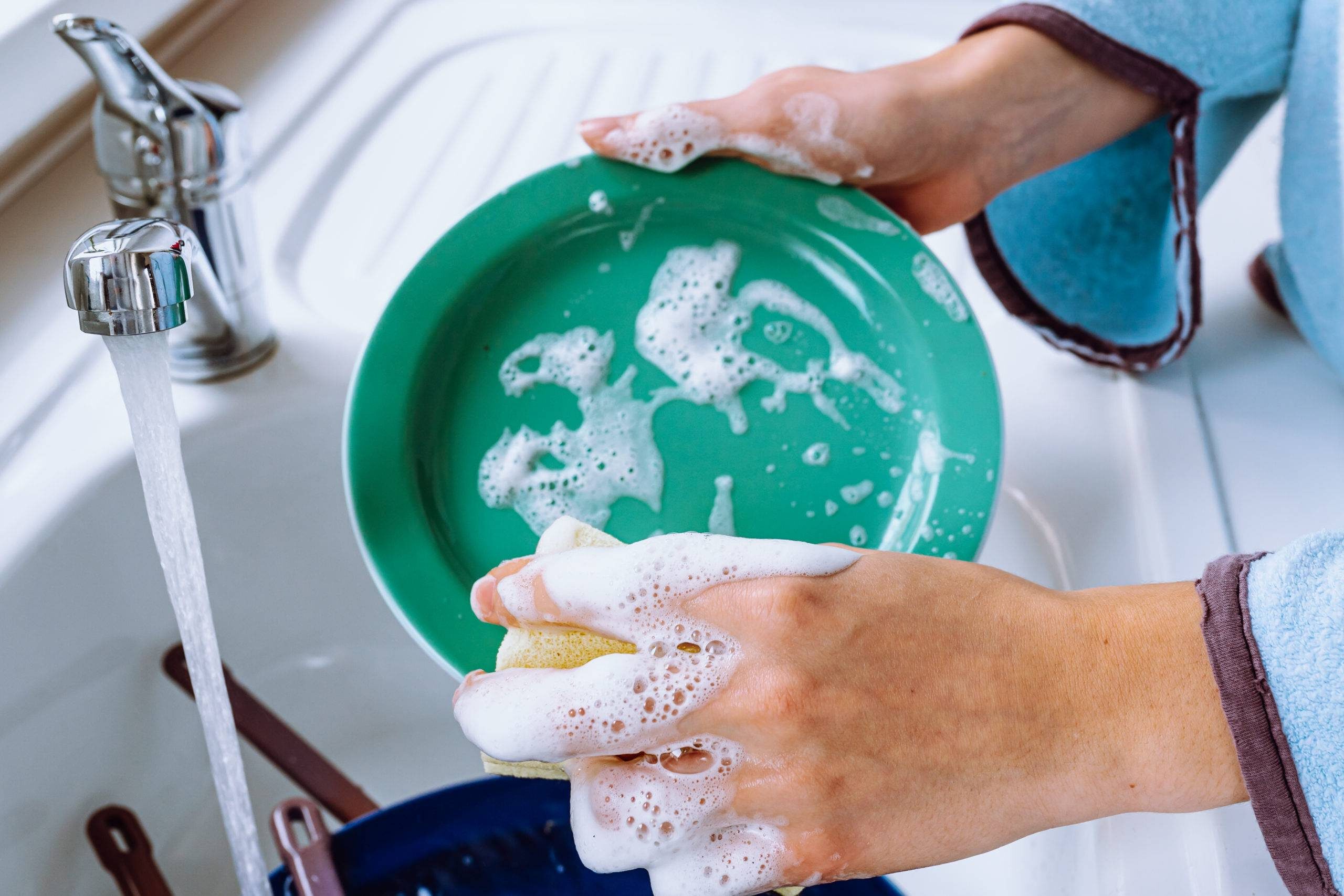 A pair of hands washing a soapy plate.