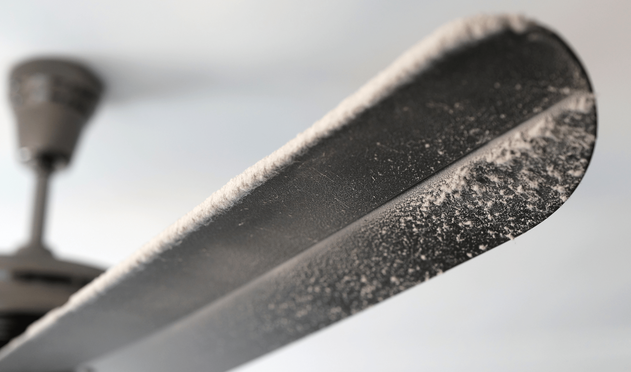A closeup of a dusty ceiling fan blade.