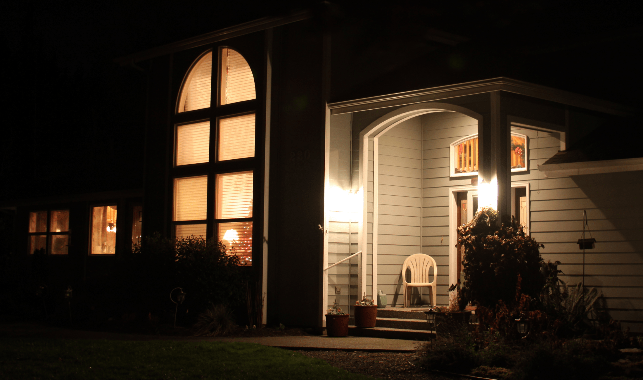 A home at night with bright lights on the porch.