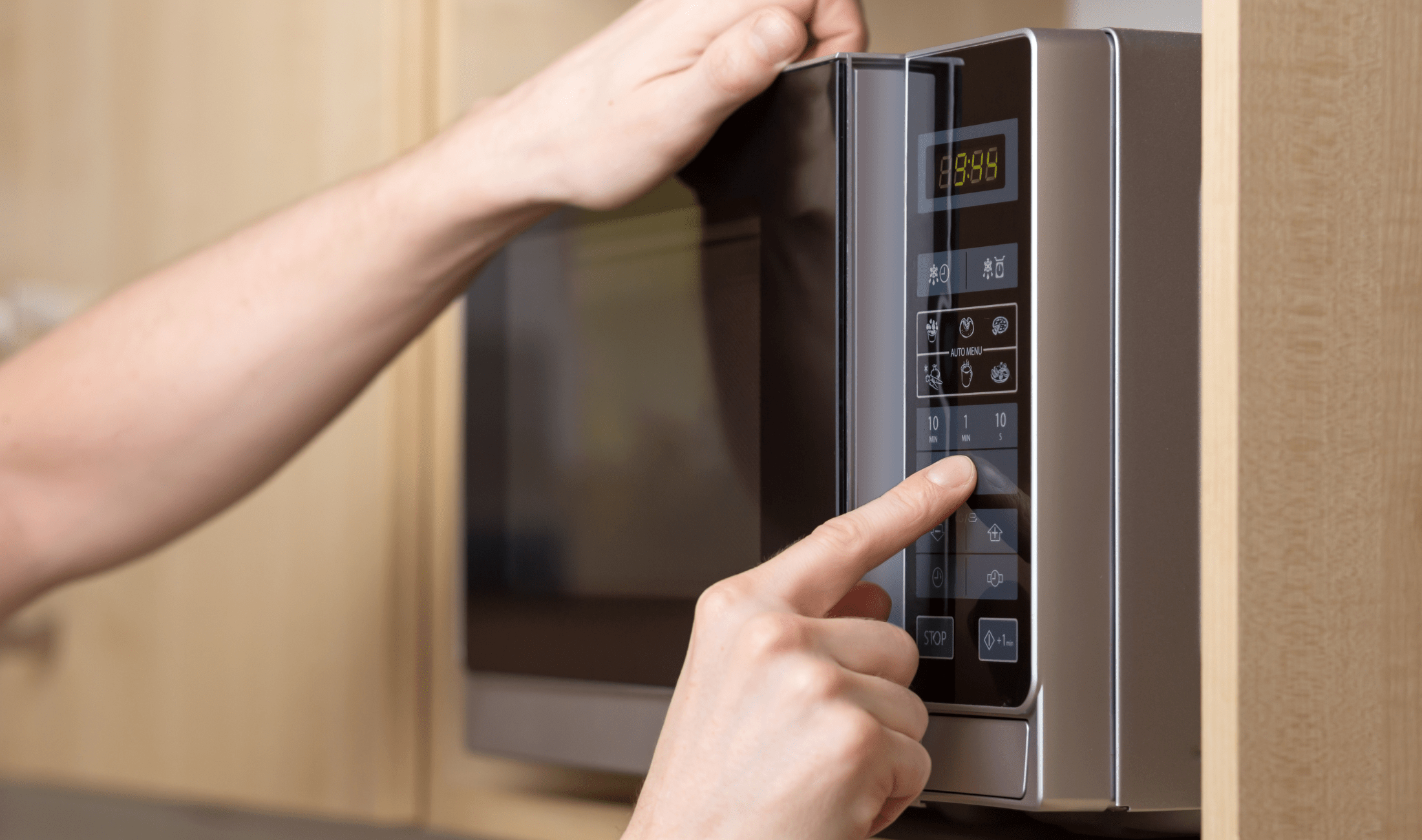 A person pushing buttons on a microwave.