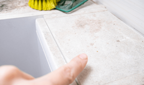 A person pointing at a dusty surface in their home.