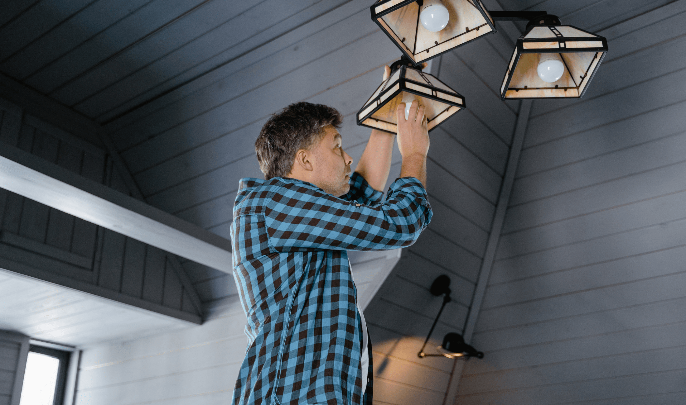 A man screwing a lightbulb into a light fixture.