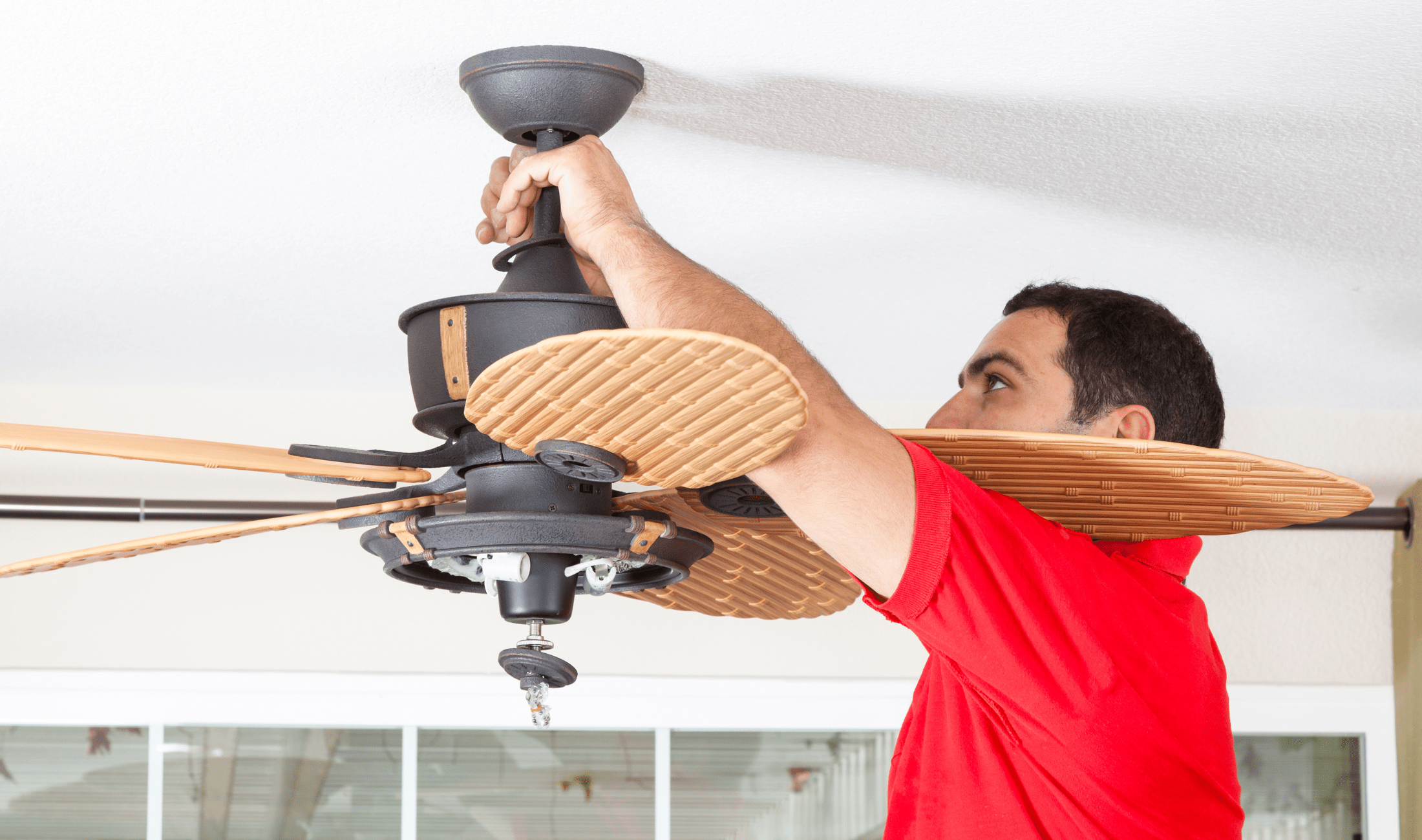A man fixing a ceiling fan.