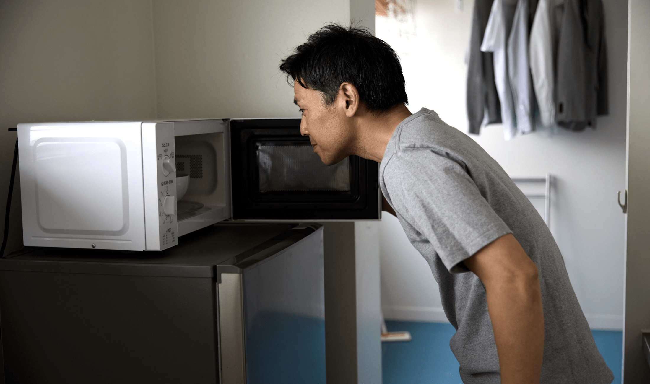 A man looking into his open microwave.