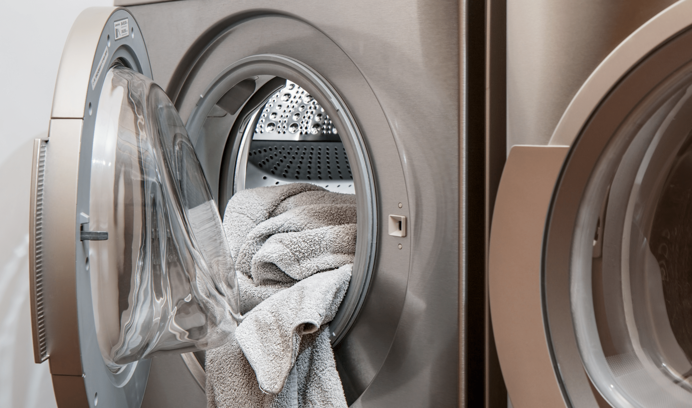 An open dryer with some towels falling out.