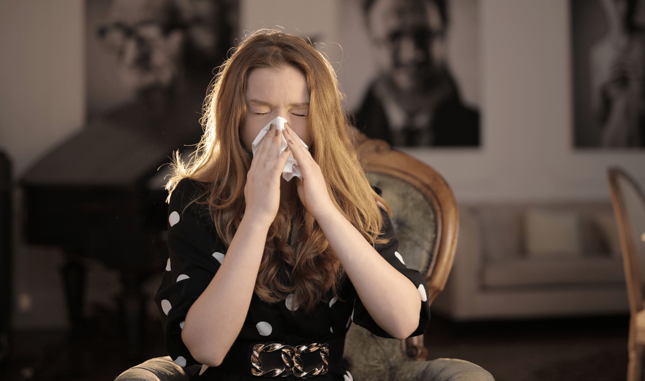 A woman sneezing into a tissue.