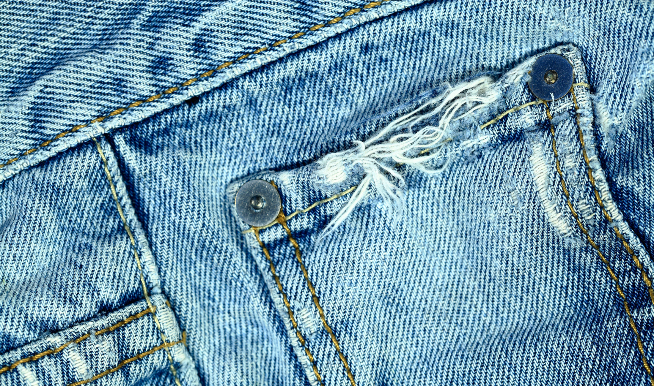 A frayed hem on a denim pocket.