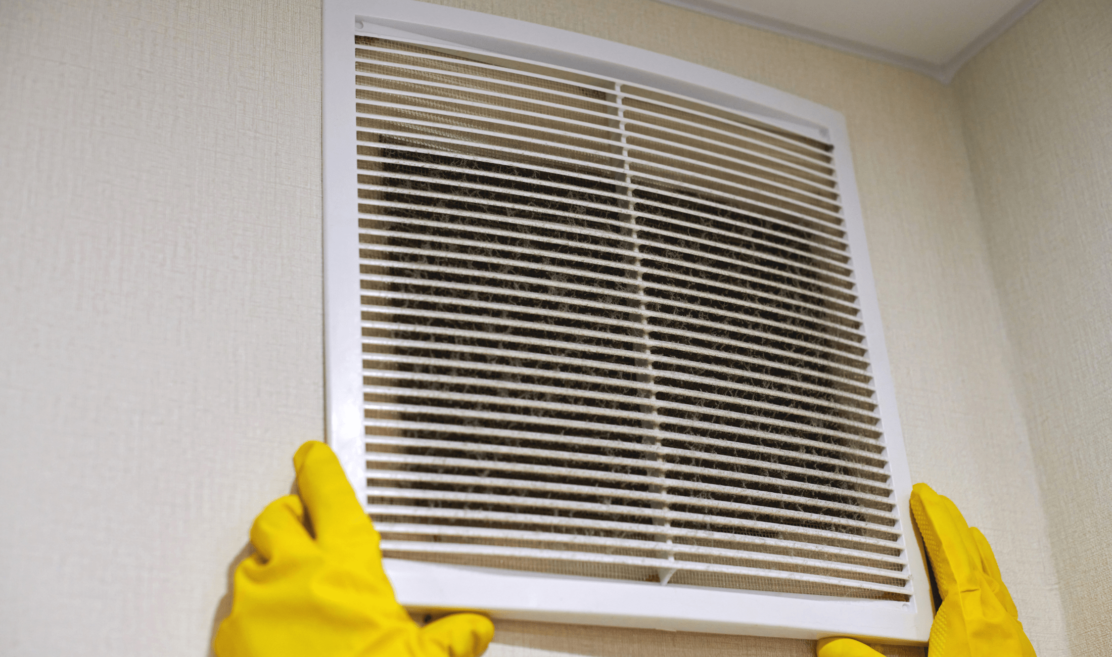 A person removing a vent cover that's full of dust.