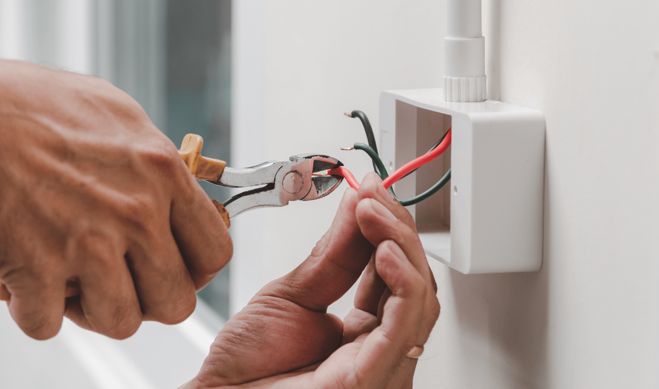 A person clipping the wires in an electrical outlet.