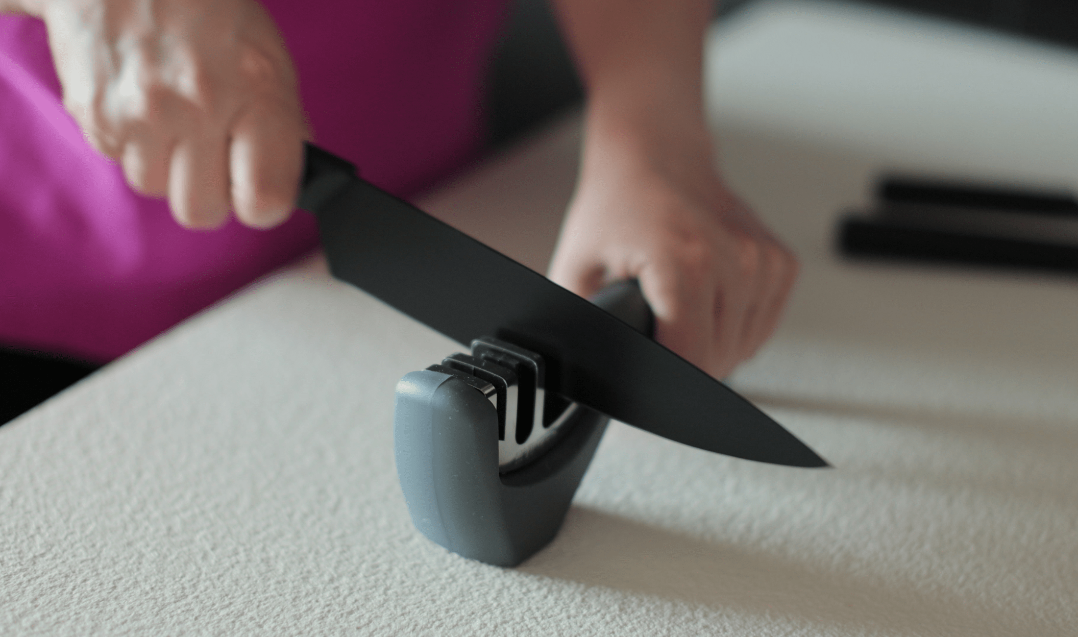 Someone using a pull-through knife sharpener.