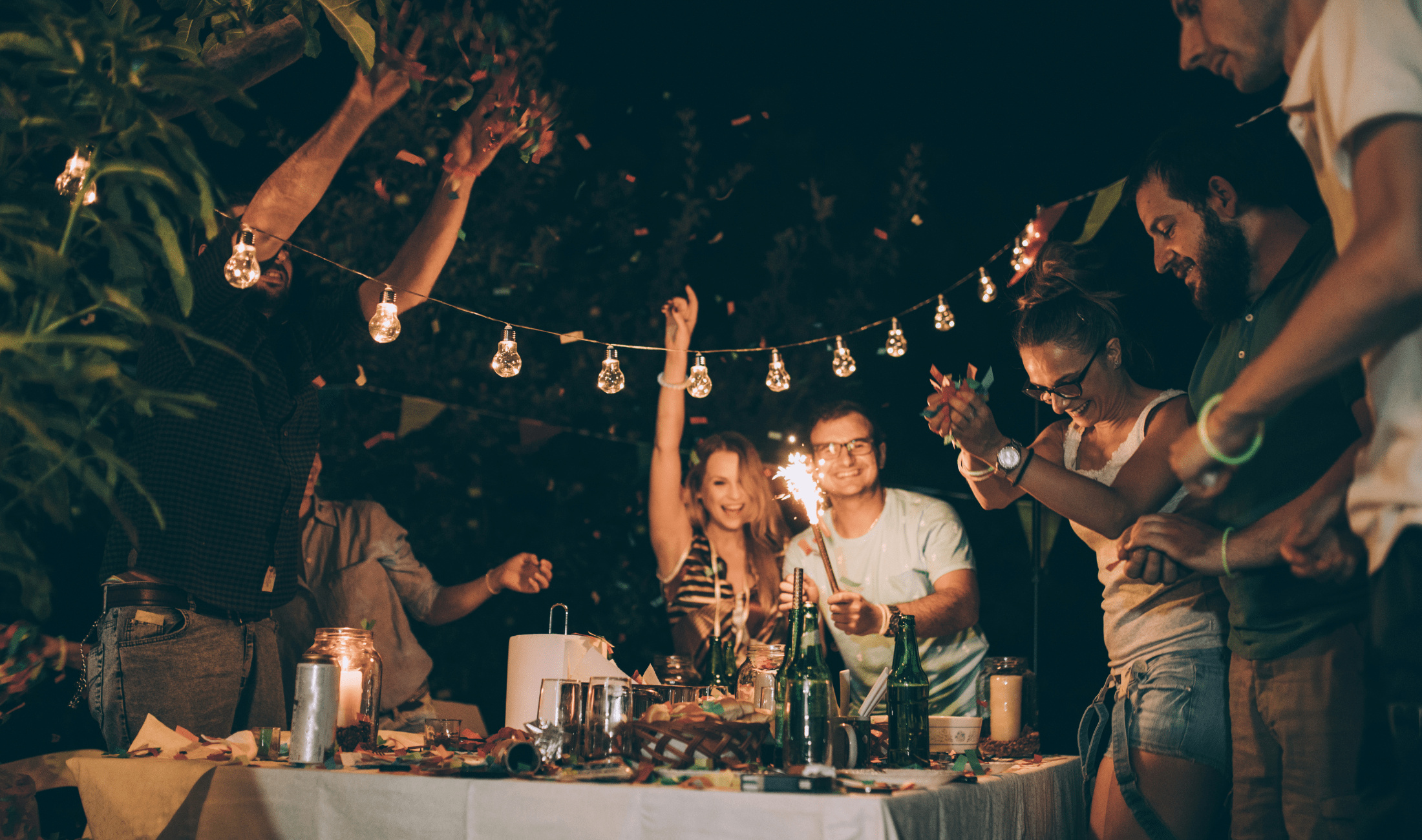A group of friends around a table outside, having a party.