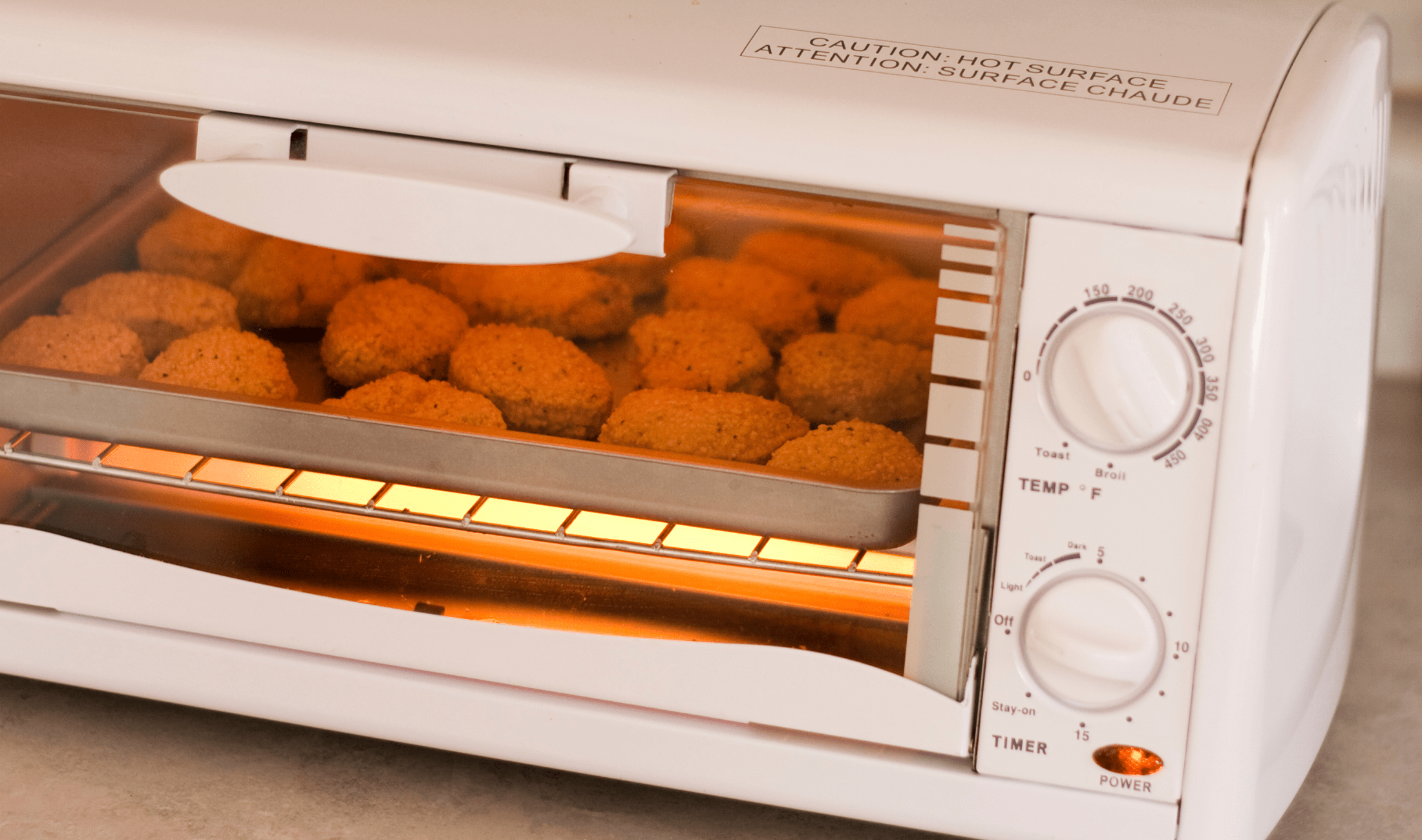 A toaster oven cooking some chicken nuggets.
