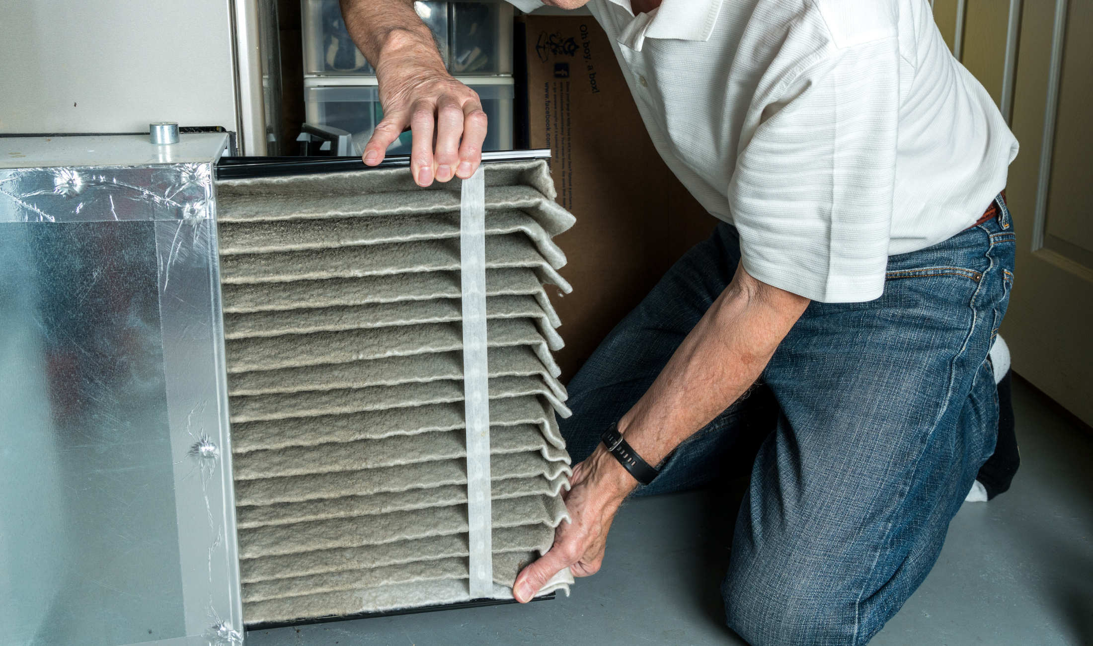 A man pulling out and revealing a very dirty HVAC filter.