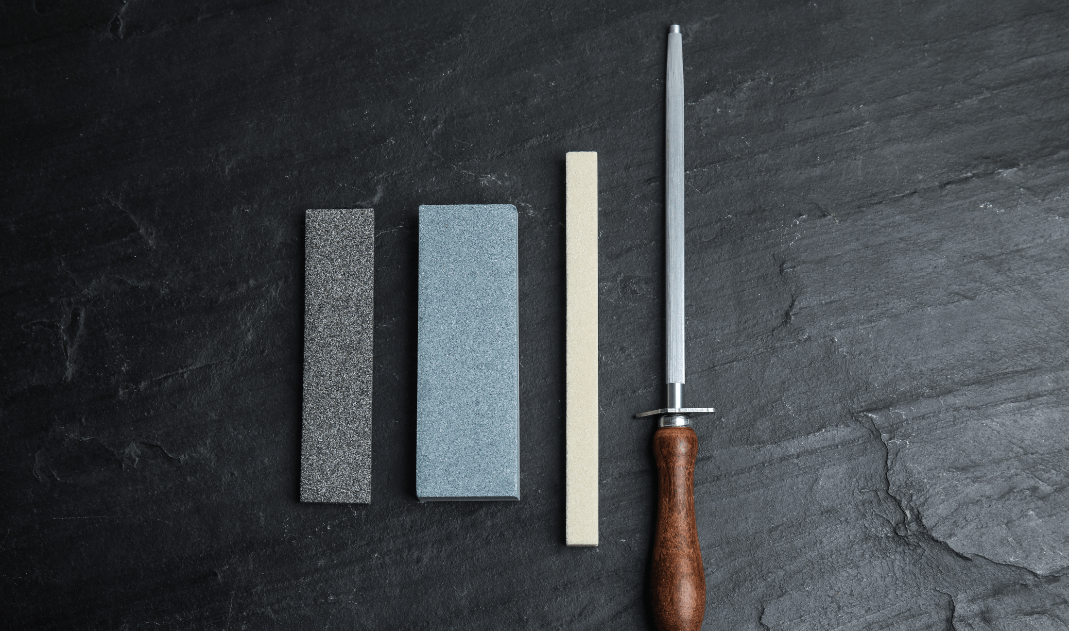 Three whetstones and a honing edge laid out parallel to one another.
