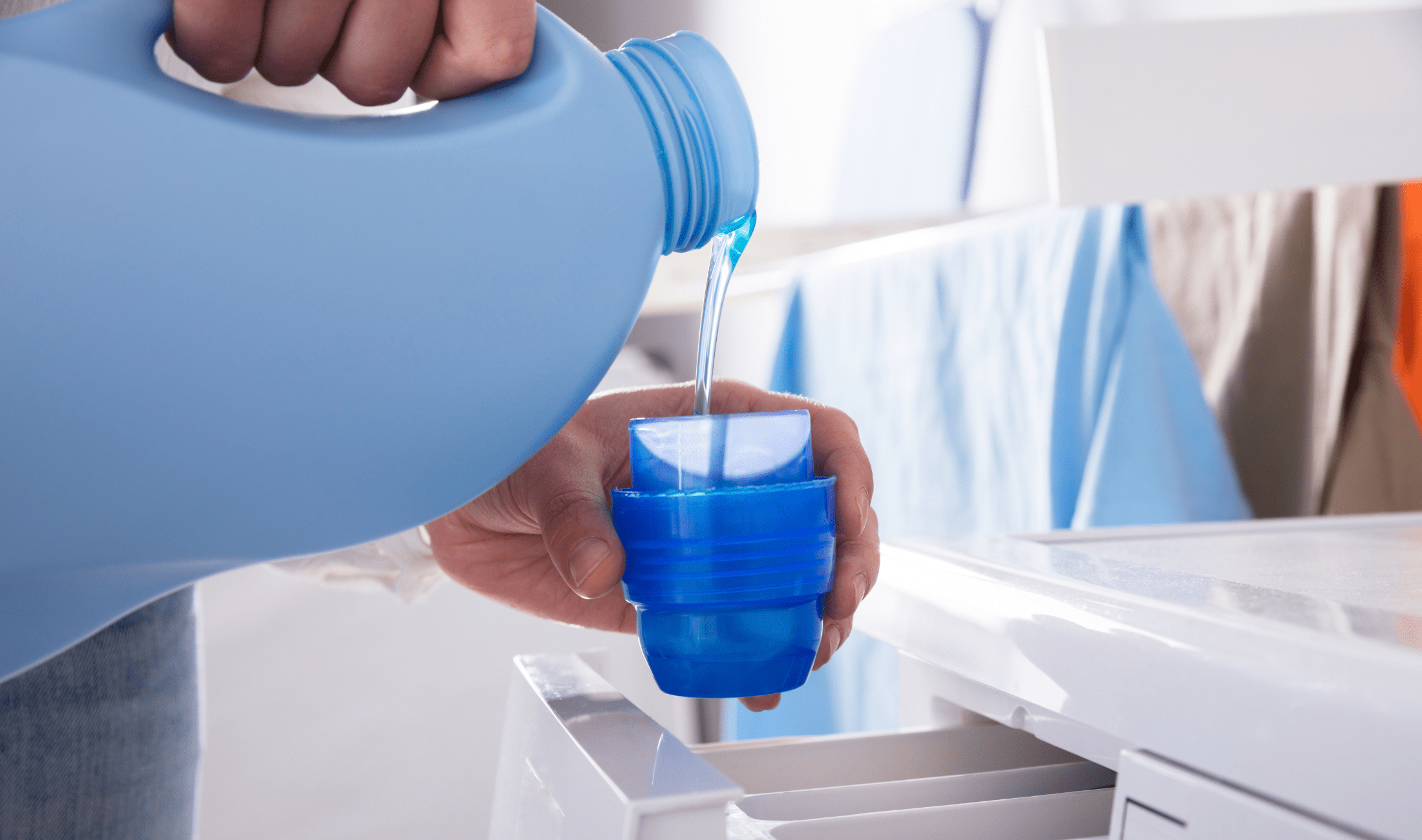 Someone pouring laundry detergent into a cup.