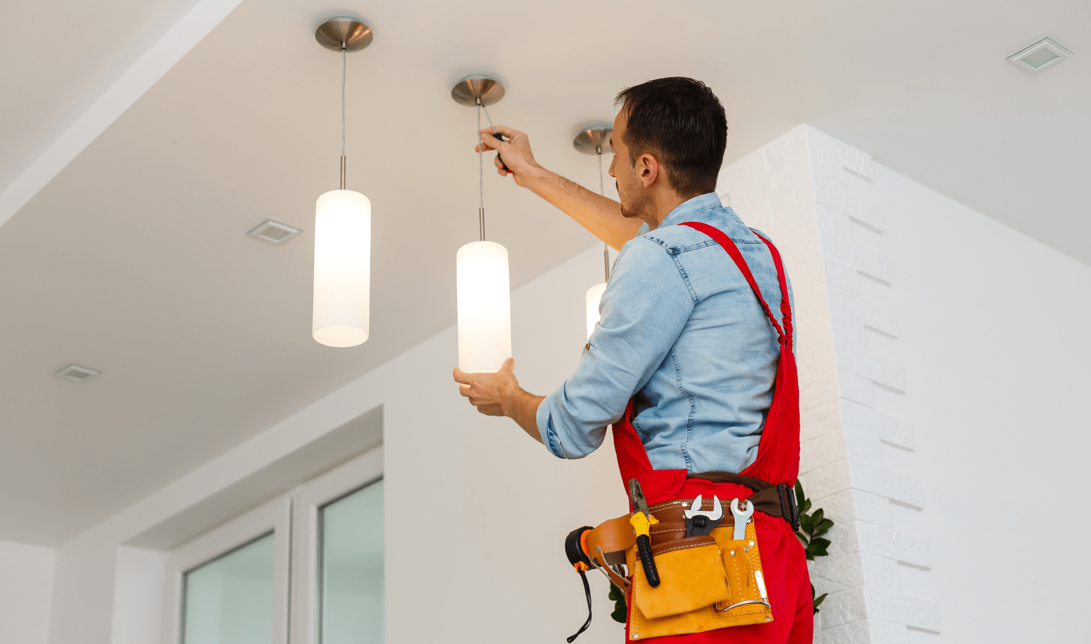 A man screwing in the plate for a new ceiling light fixture.