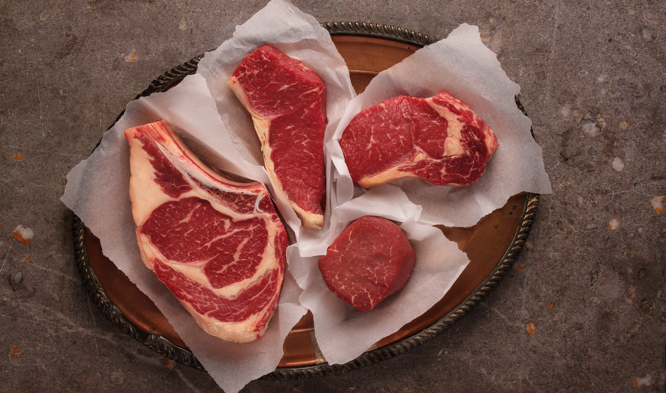 Four varying cuts of raw steak.