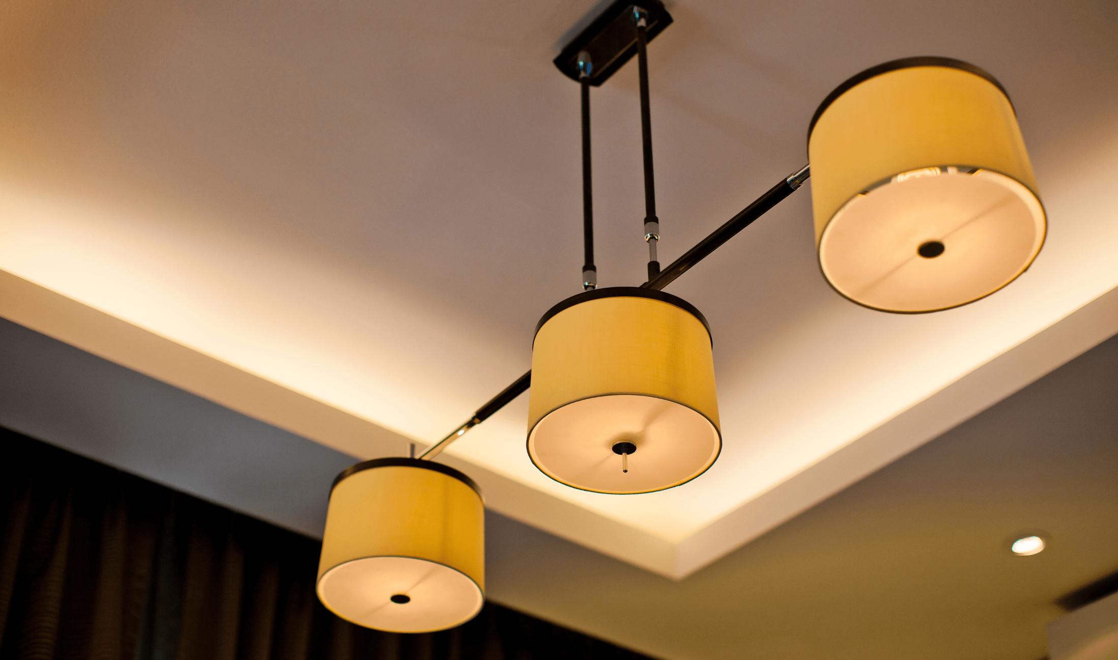 A low angle shot of a ceiling light fixture with three small shades on it.