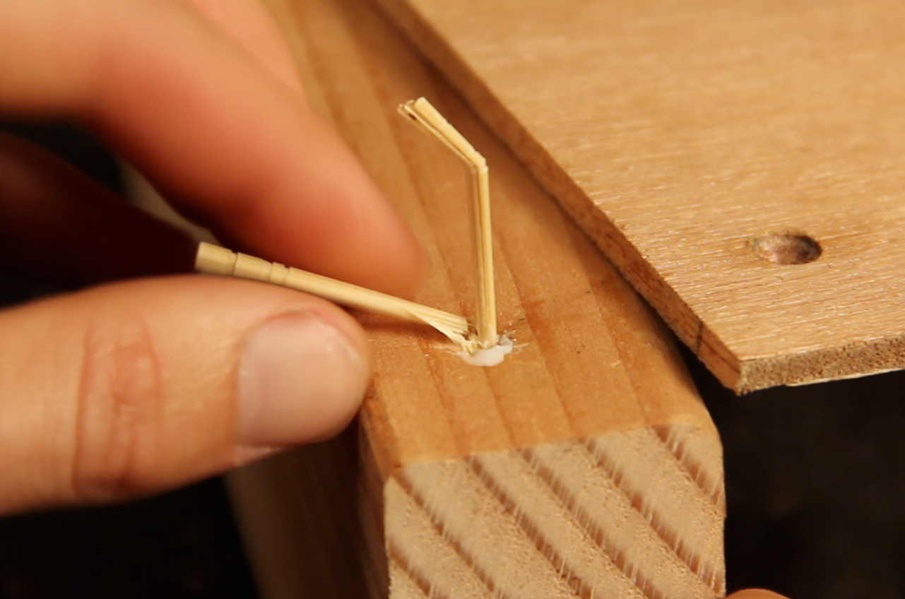 A person breaking a few matchsticks they had stuck into a stripped screw hole.