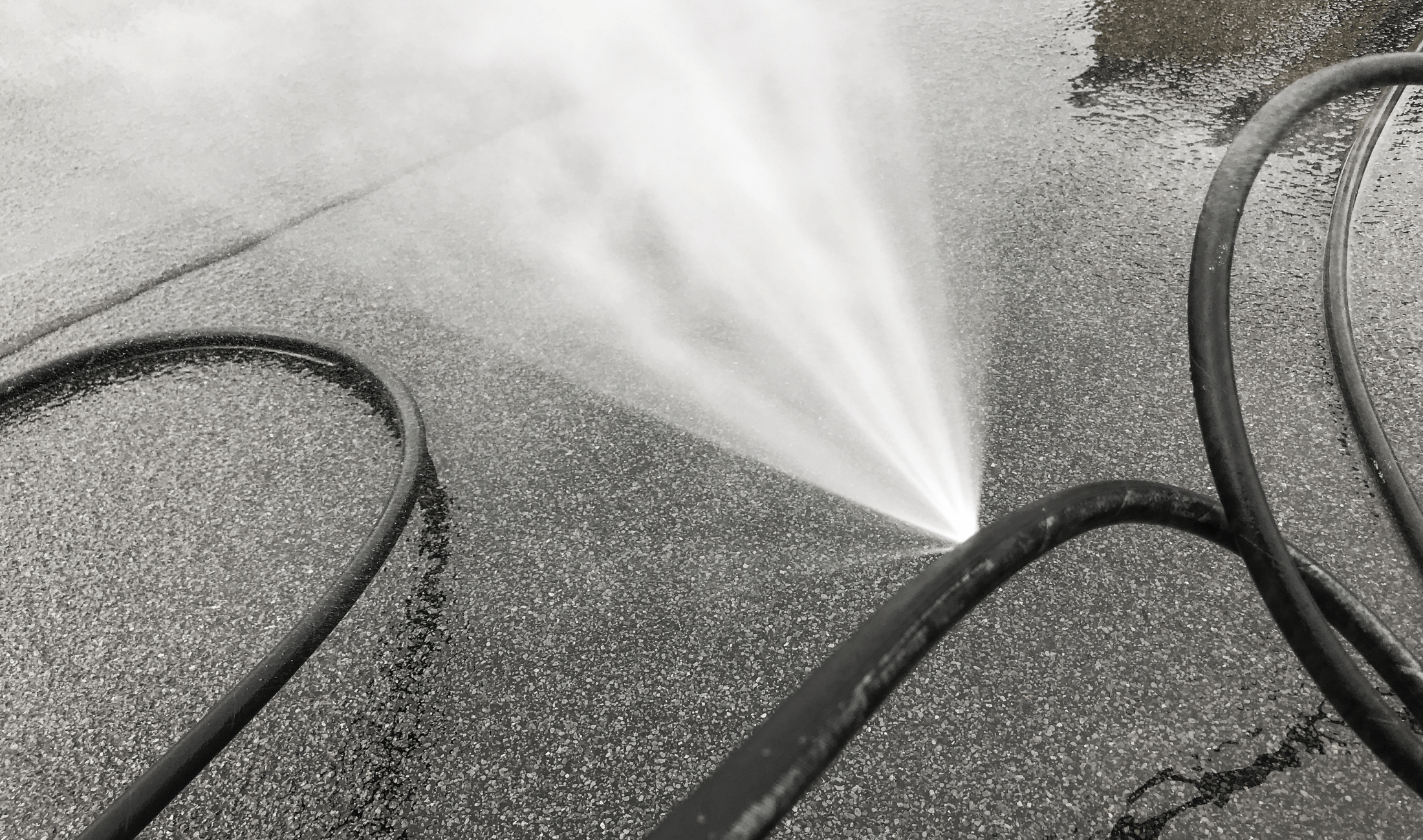 A garden hose bursting with water through a hole in the side.
