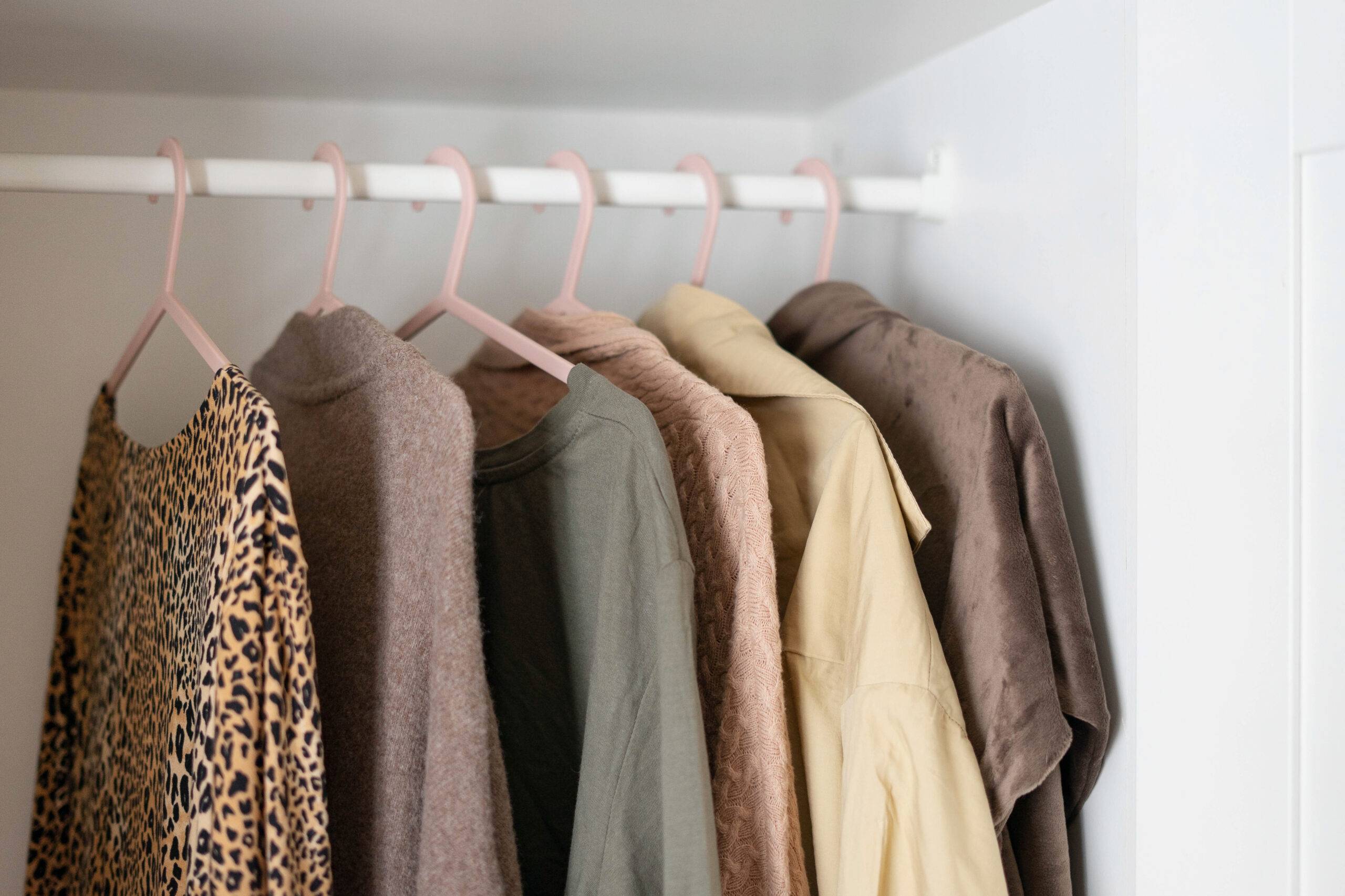 Capsule basic wardrobe in a white wardrobe in brown and beige colors. Autumn clothes on hangers.