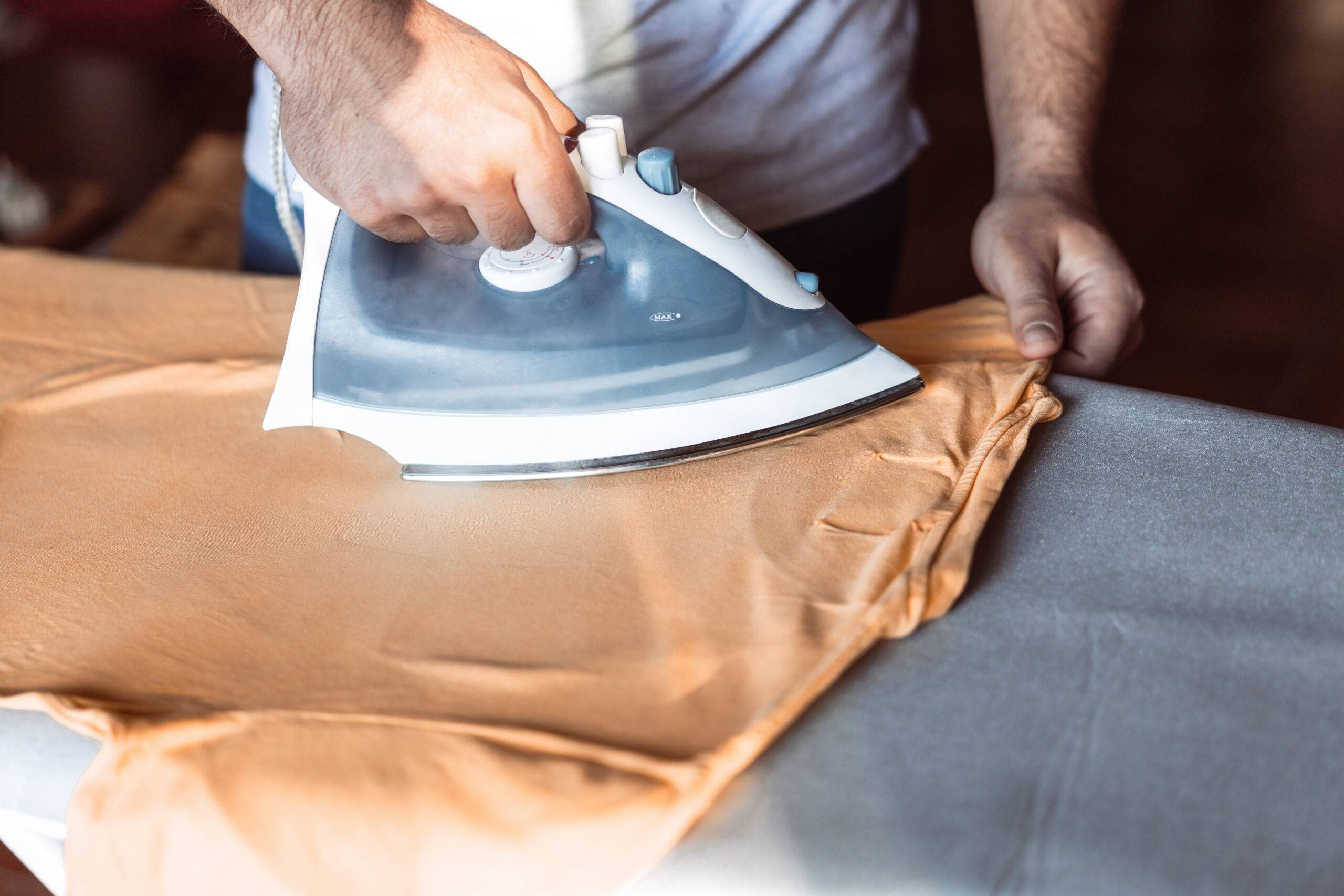 Close-up of a man's hands ironing a T-shirt.