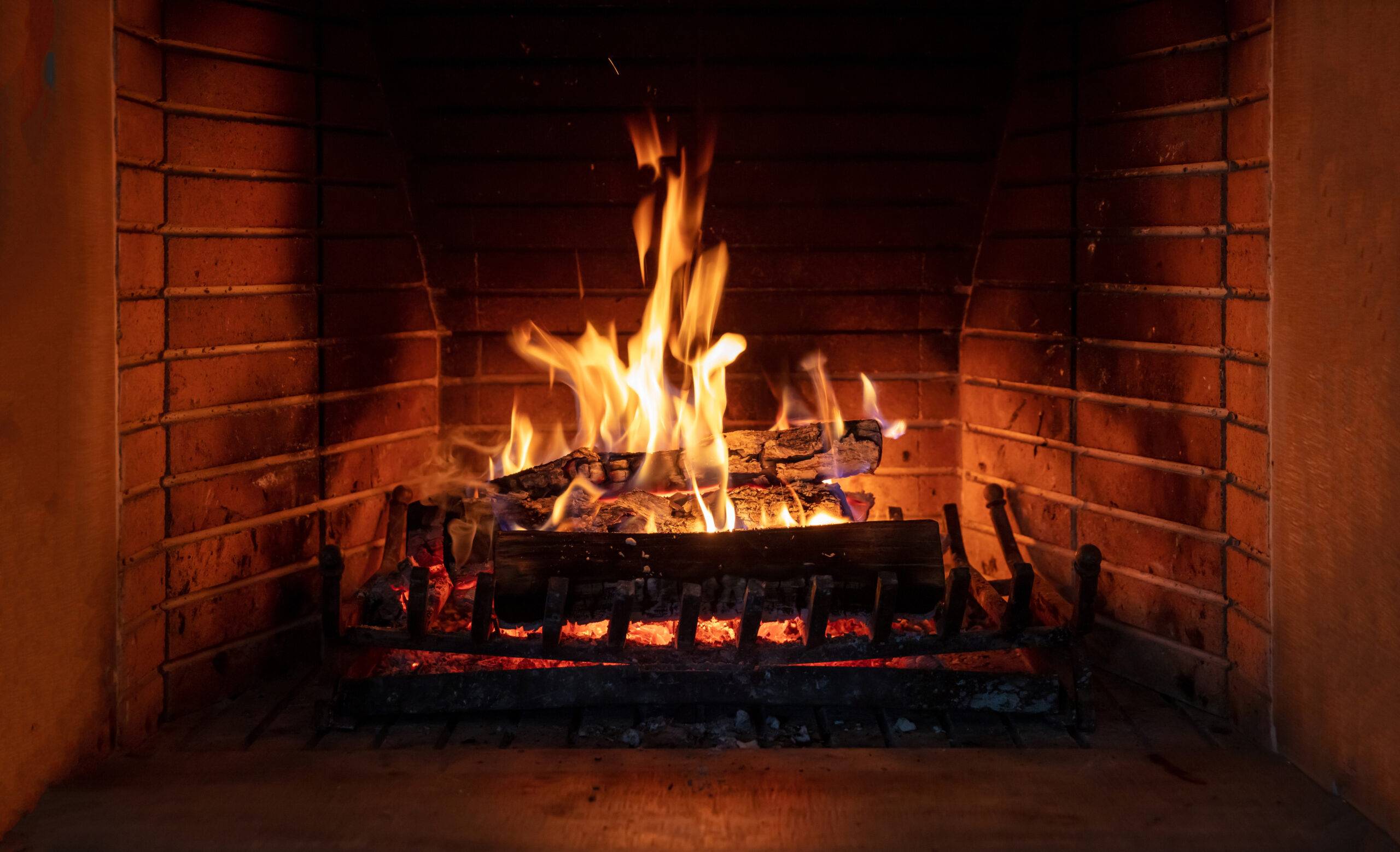 Fireplace, cozy warm fireside. Fire burning, logs flaming, firebricks background. Relaxation at home winter holiday christmas time