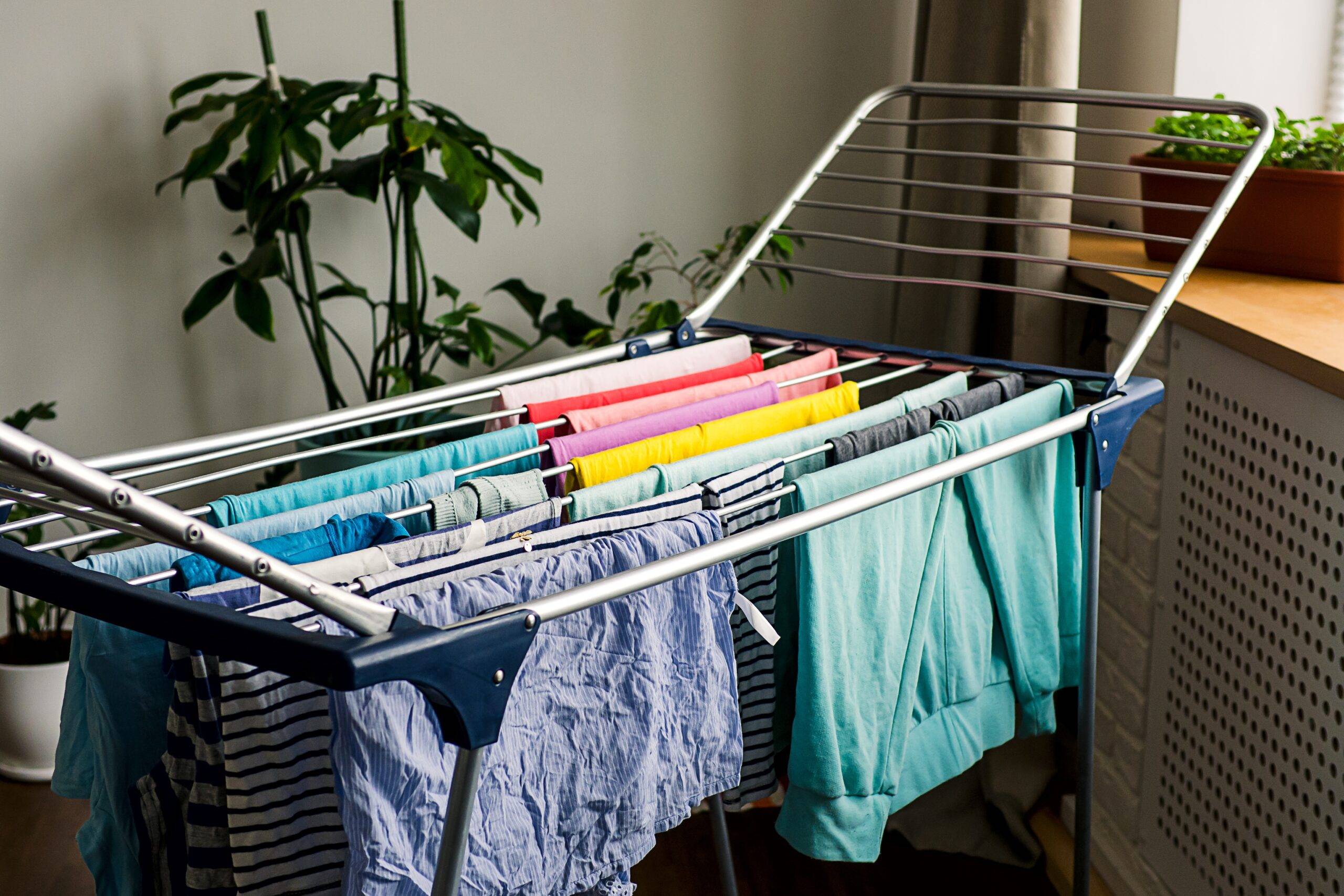 Laundry day Rainbow color clothes hanging on washing line to dry indoors home.