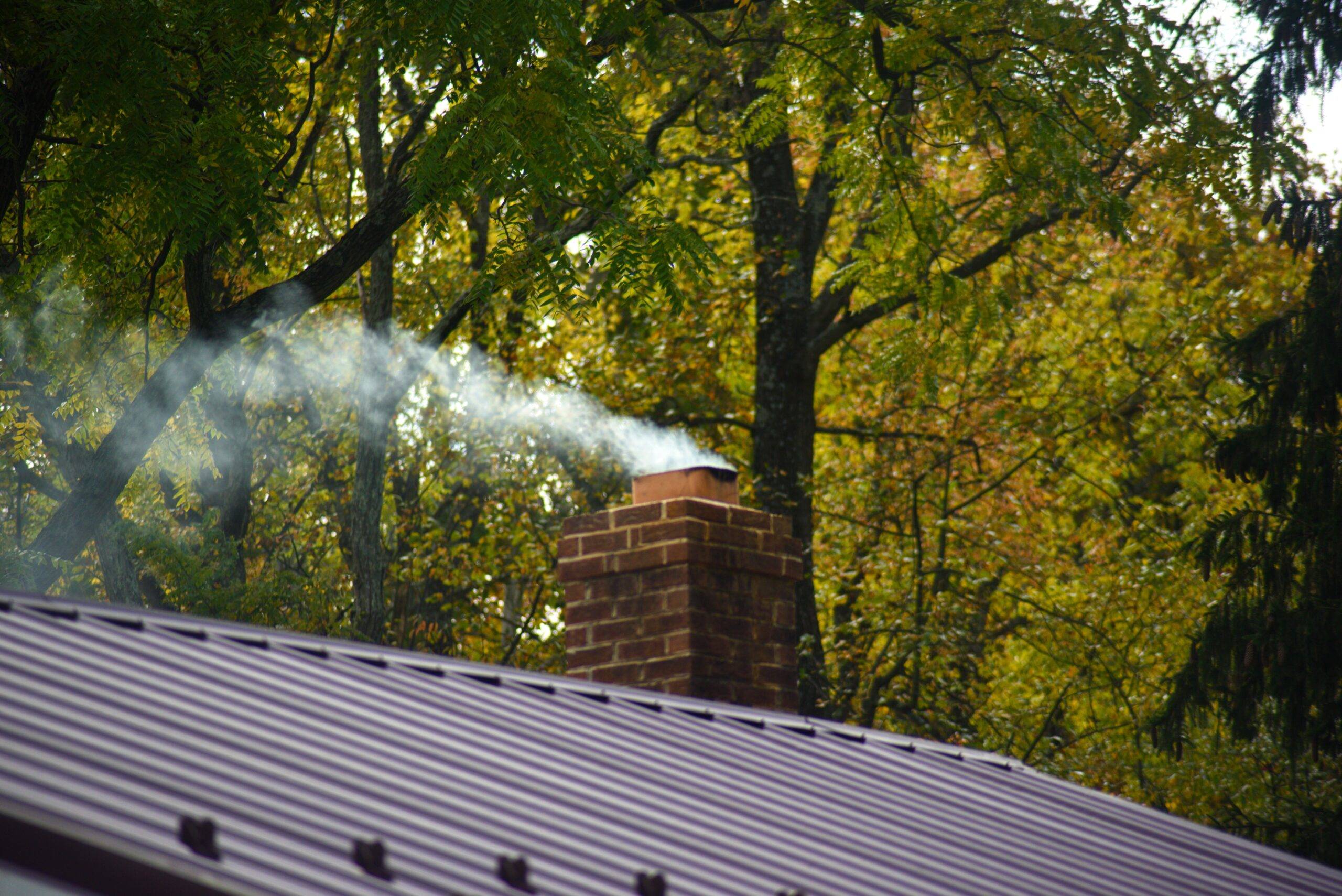 Smoke exiting a brick chimney on a home.
