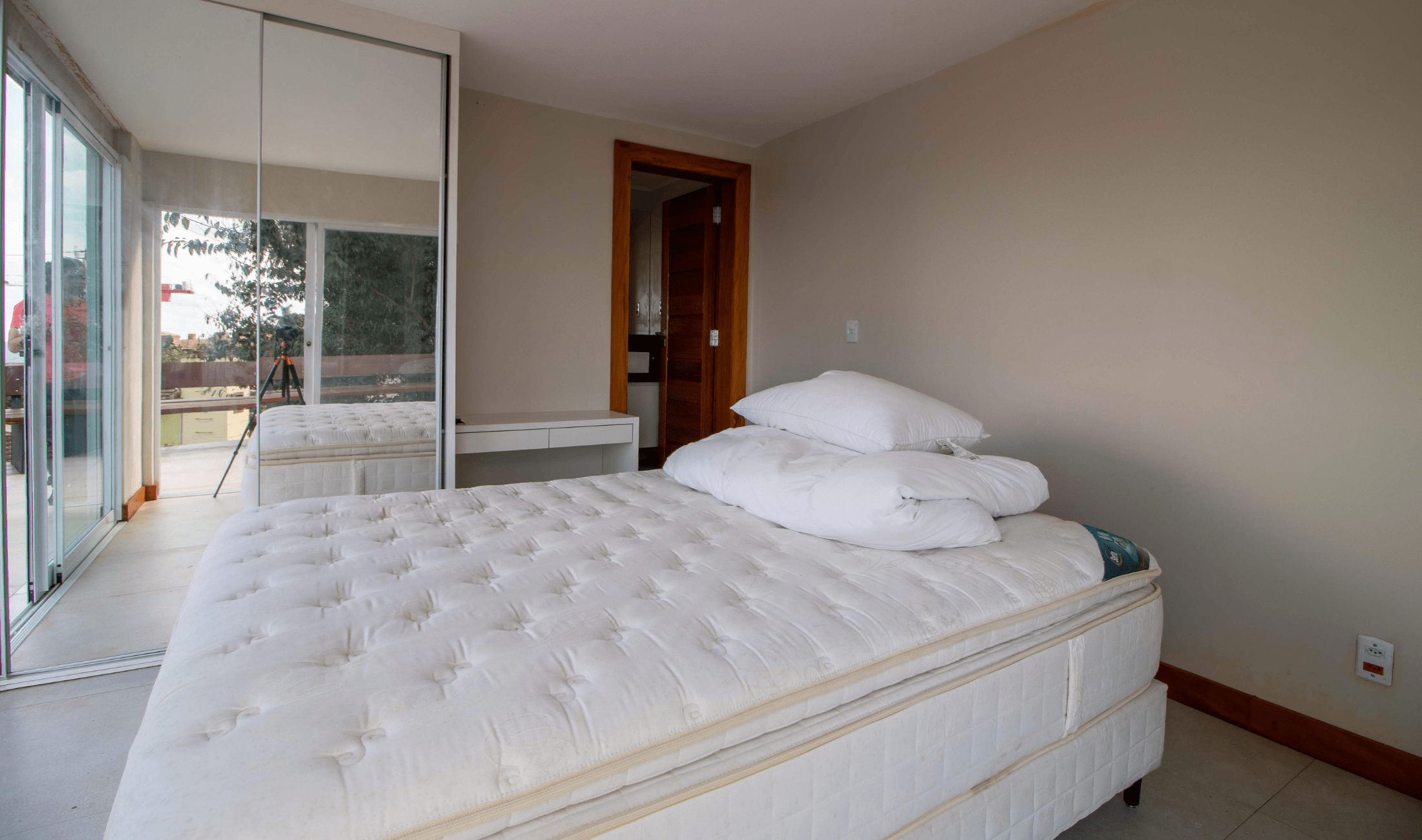 A bare mattress on a bed in the middle of a room.