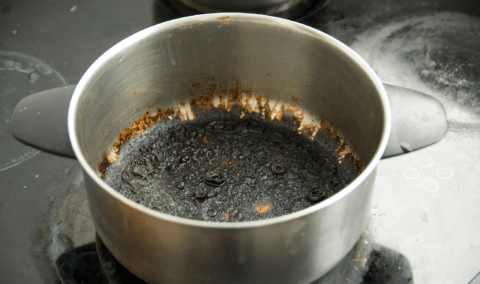 A pot with a layer of burnt food on the bottom.
