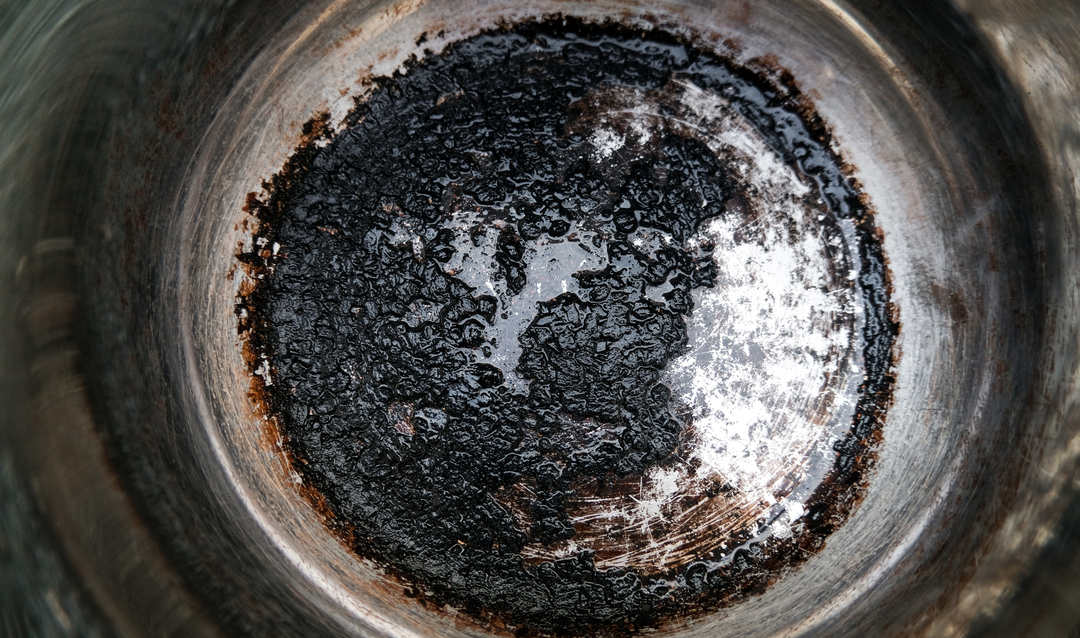 A pot with a layer of burnt food on the bottom.