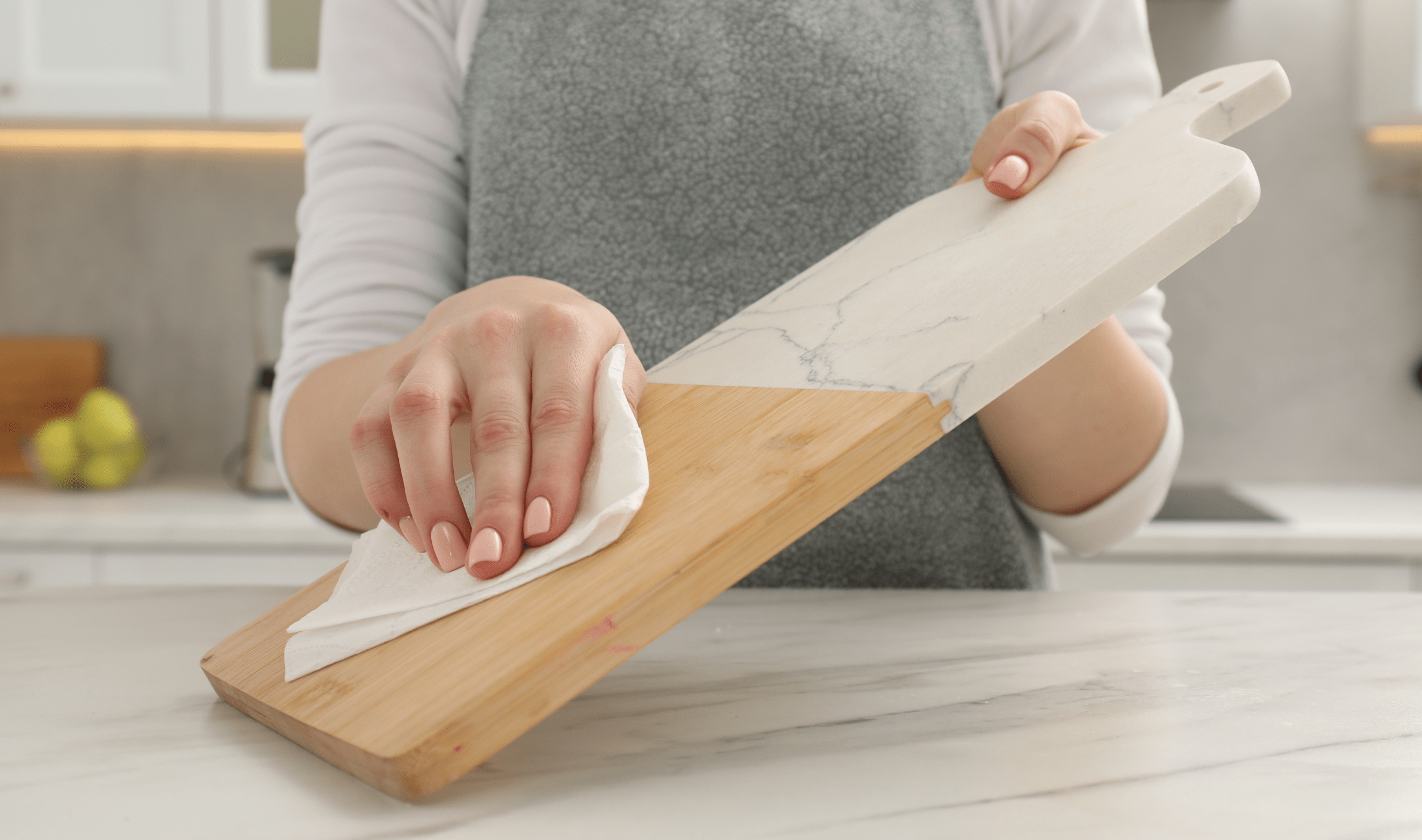 A woman's hand using a disinfectant wipe to clean a serving board.