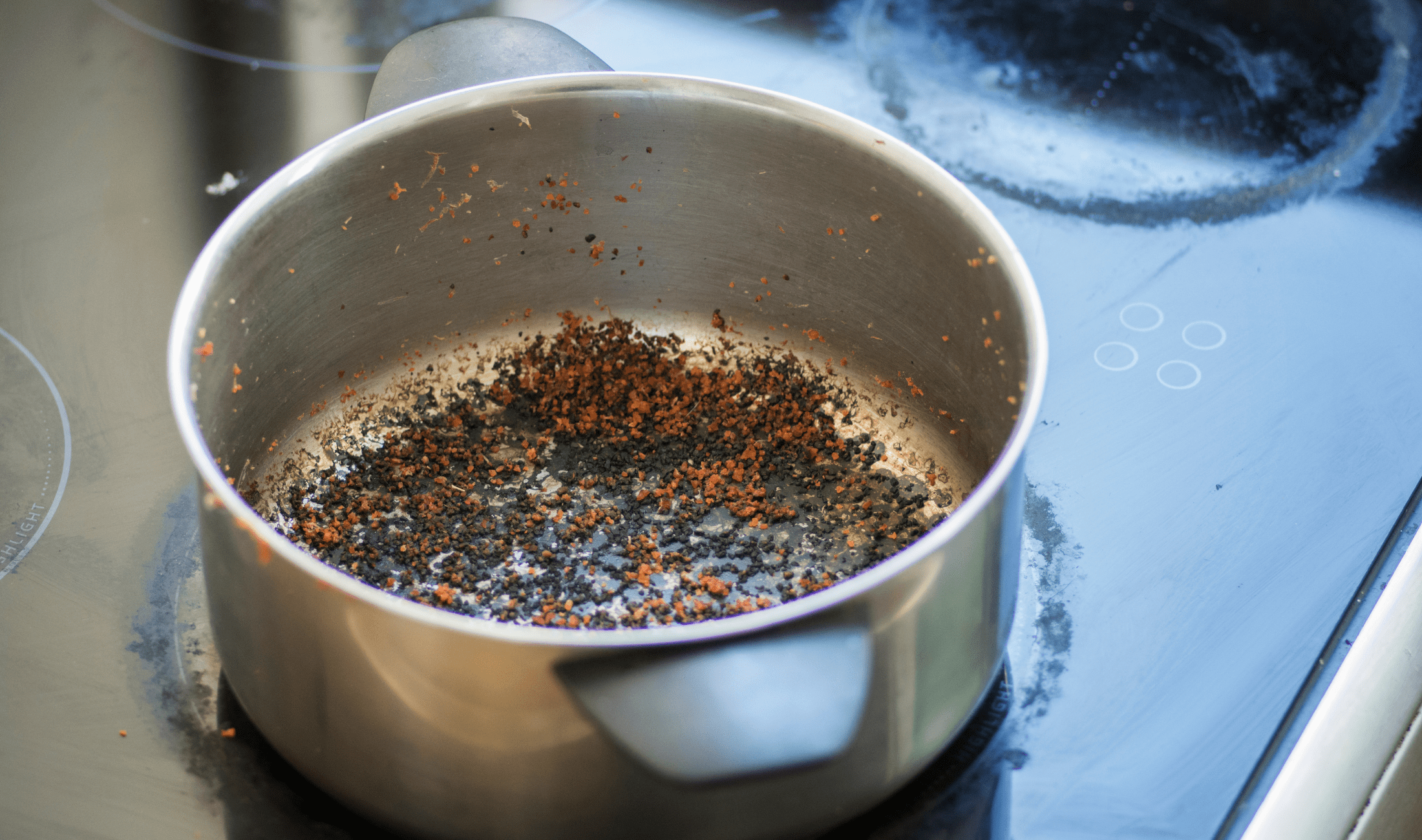 A pot with a layer of burnt food on the bottom.