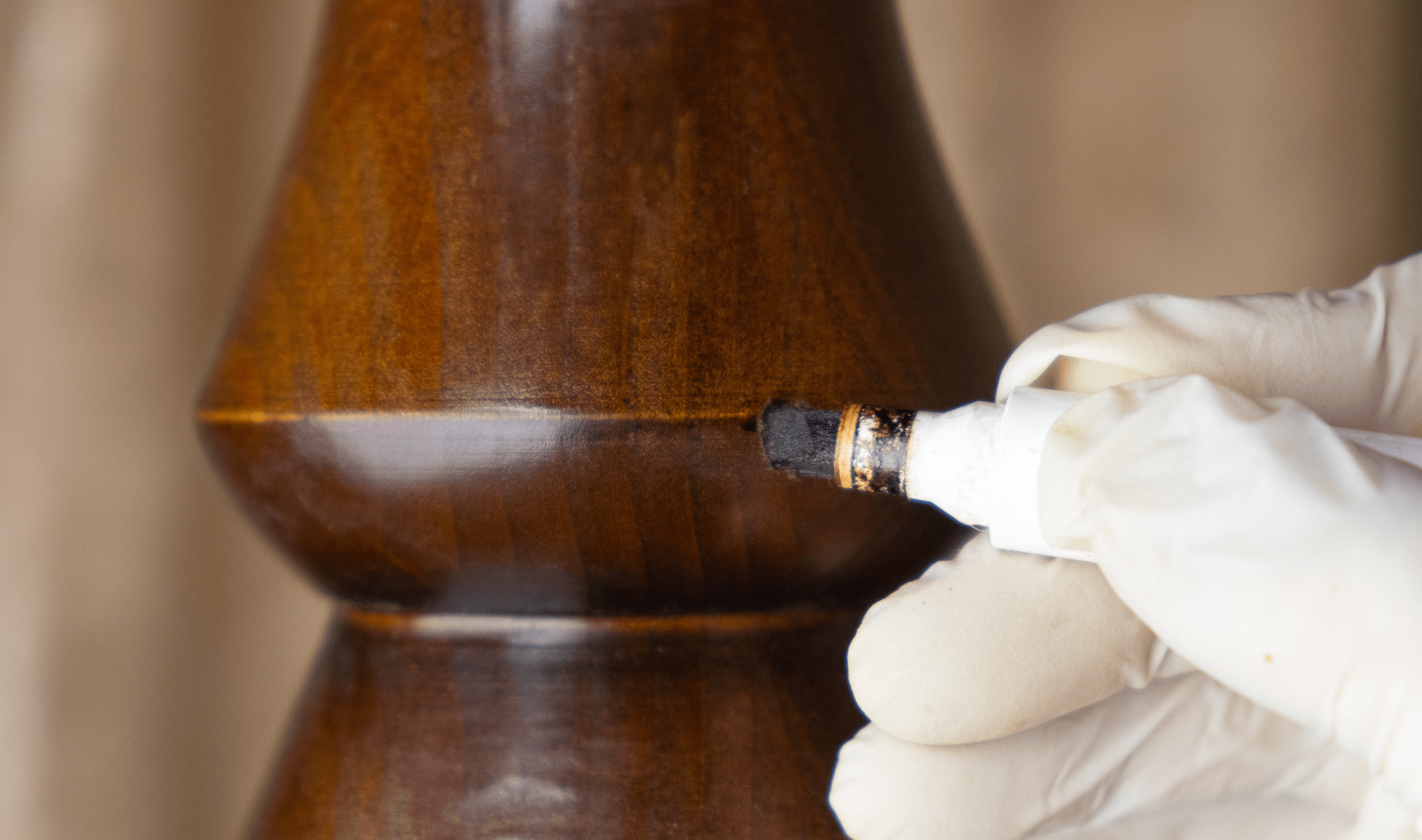 A close photo of someone using a wood repair marker on a banister.