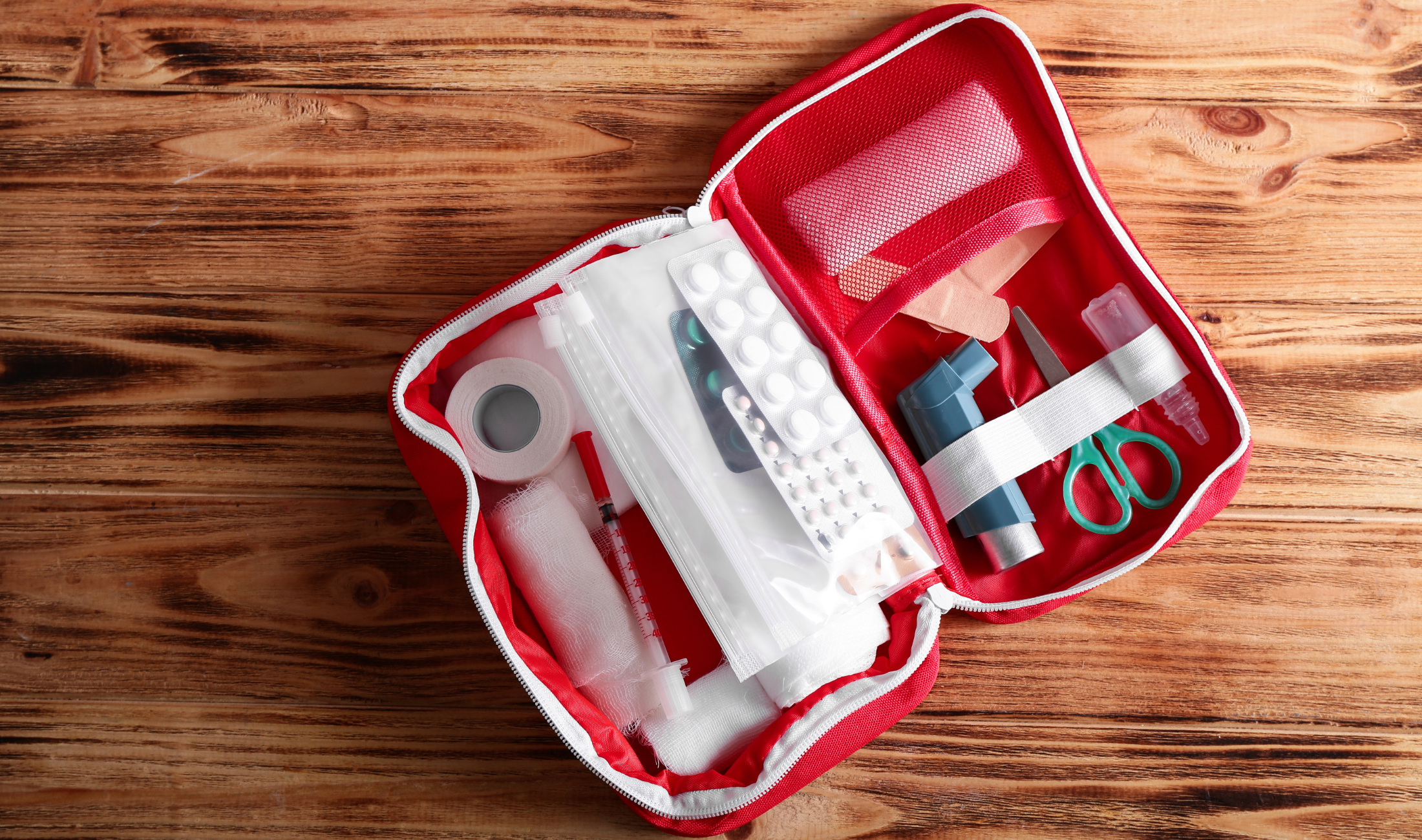 An open first aid kit on a wood table.