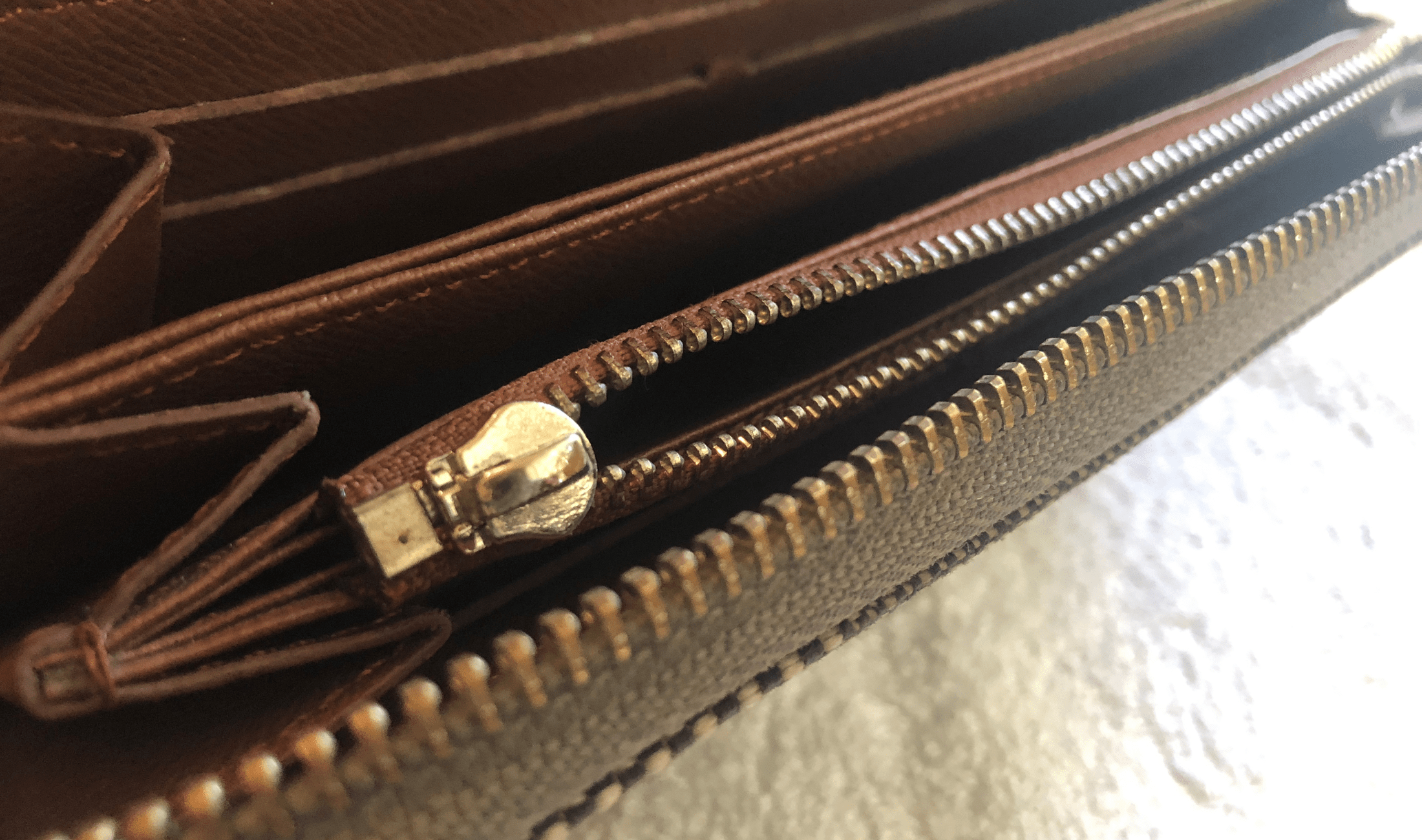 A closeup of a wallet's broken zipper.