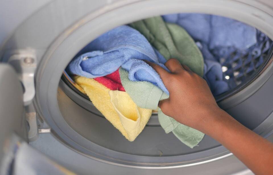 A person putting cloths in a washing machine.