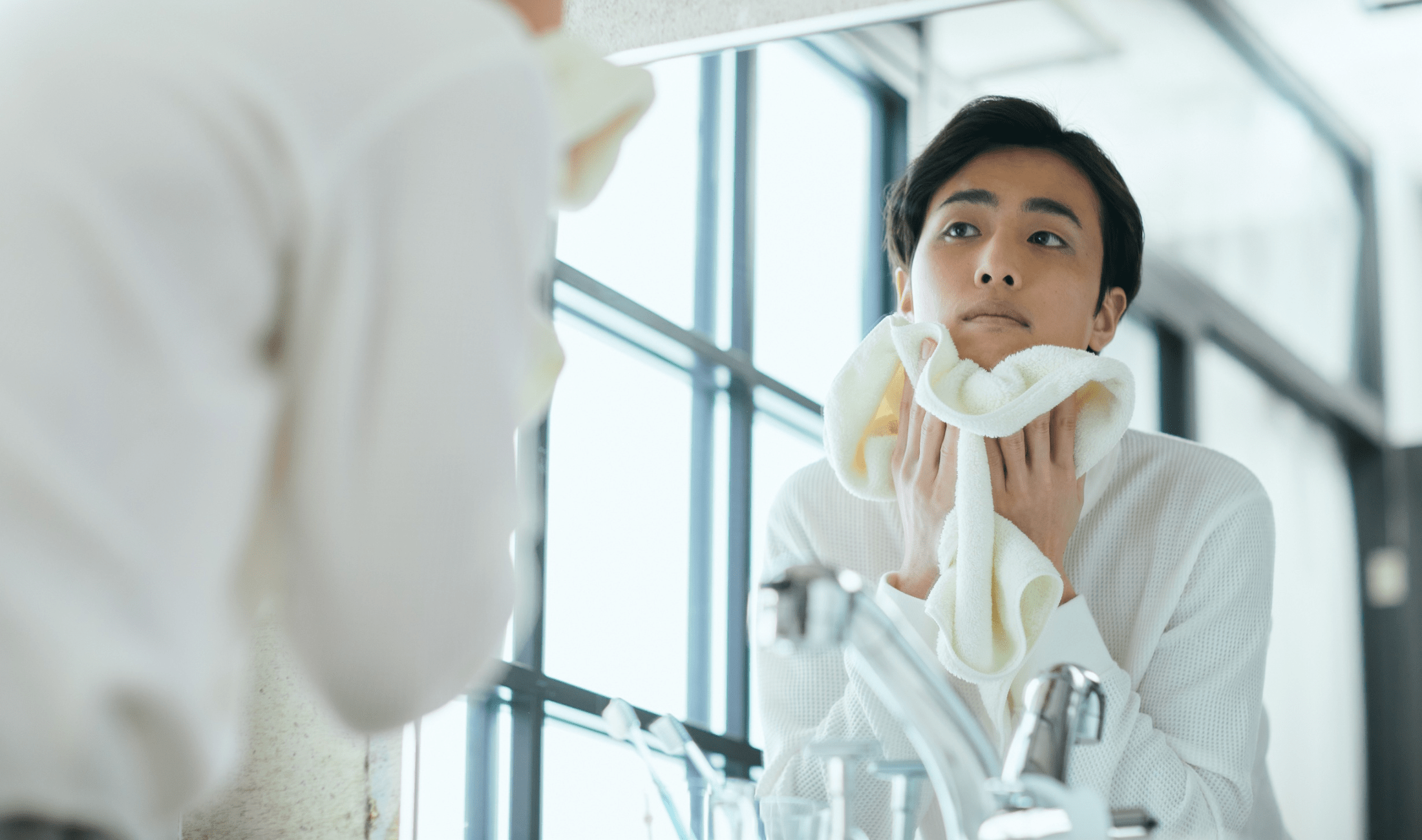 A man drying his face with a white hand towel.