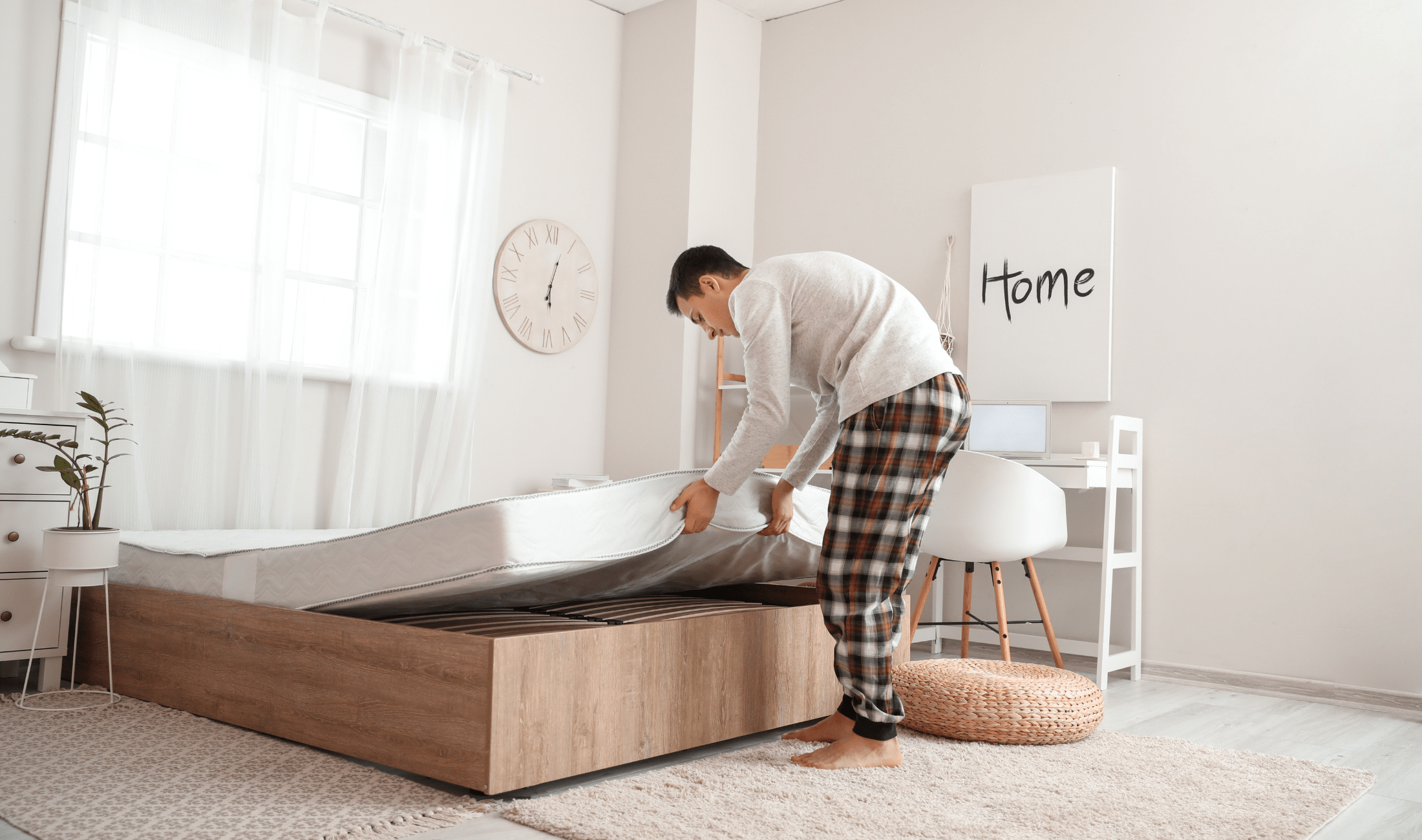 A man putting a mattress back on his bedframe.