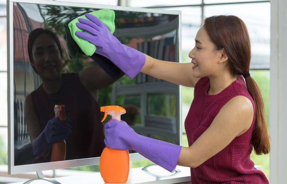 A woman cleaning a tv.