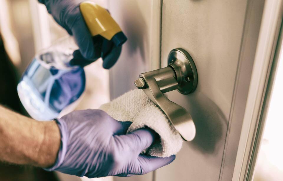 A person cleaning door handles.