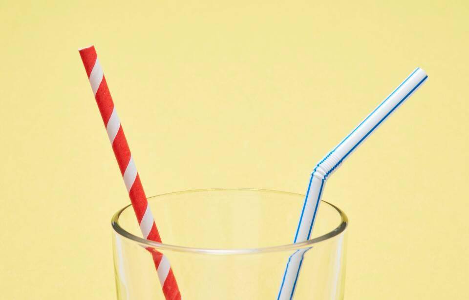 Two different straws sticking out of a glass.