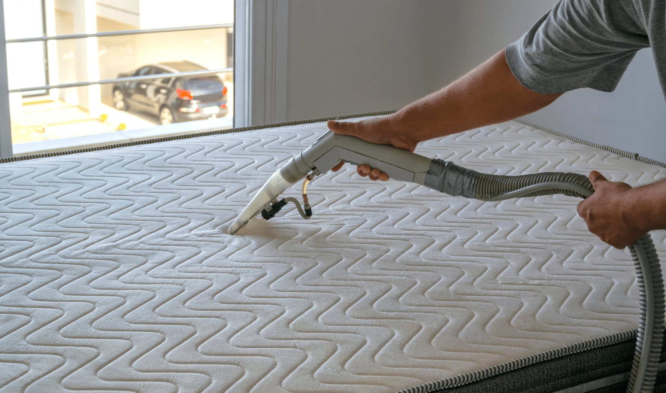 A person vacuuming a mattress.