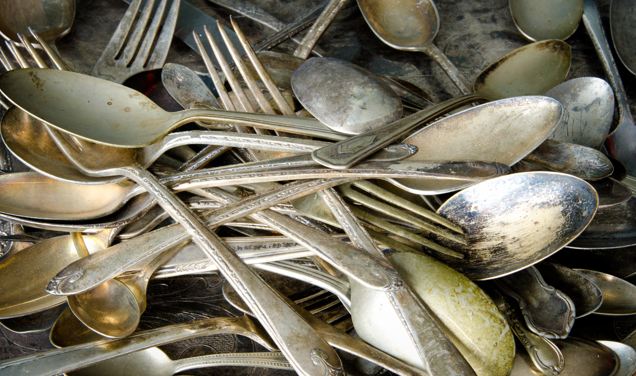 A pile of tarnished, mismatched silver cutlery