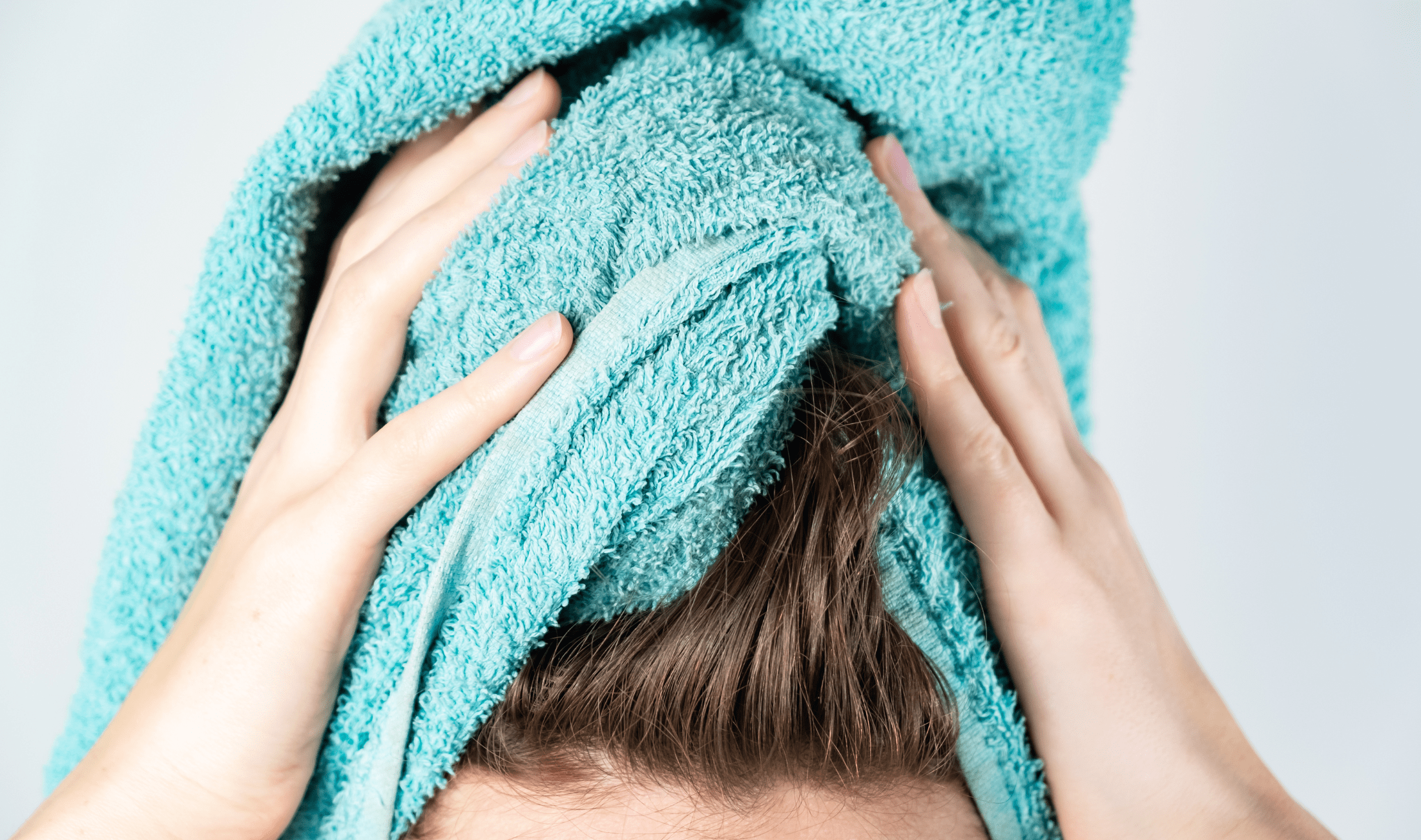 A close photo of a woman wrapping her hair in a blue towel.
