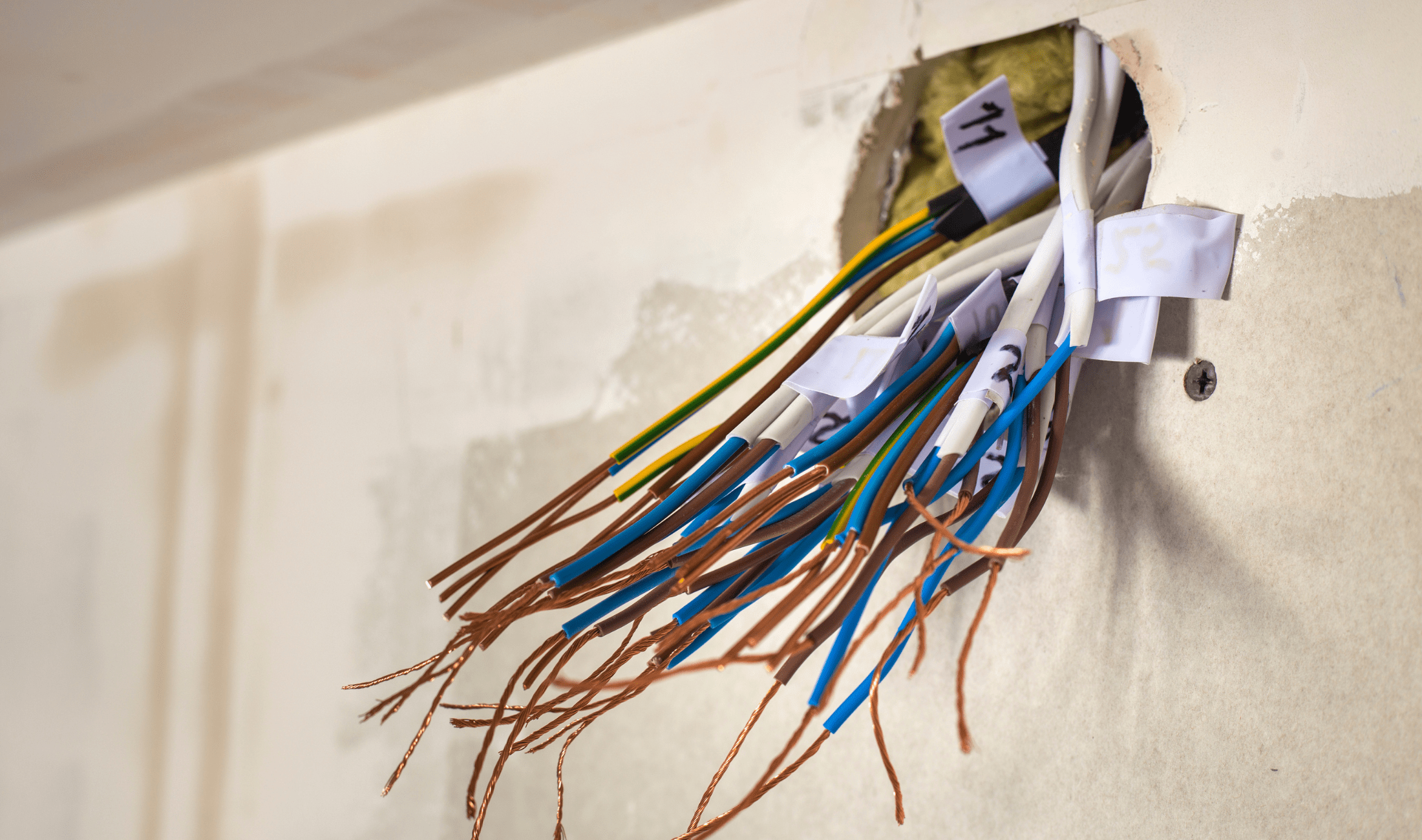 A hole in a wall with a large bundle of wires.