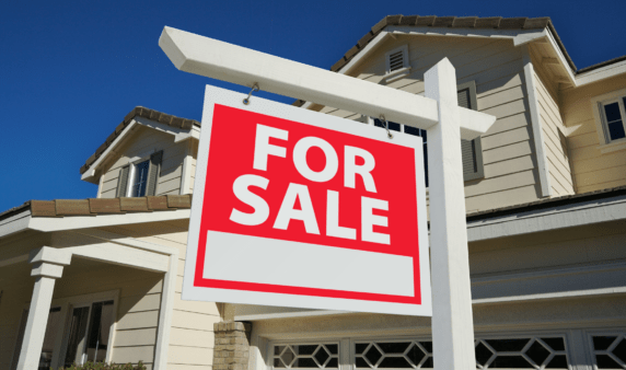 A large, red for sale sign in front of a house.